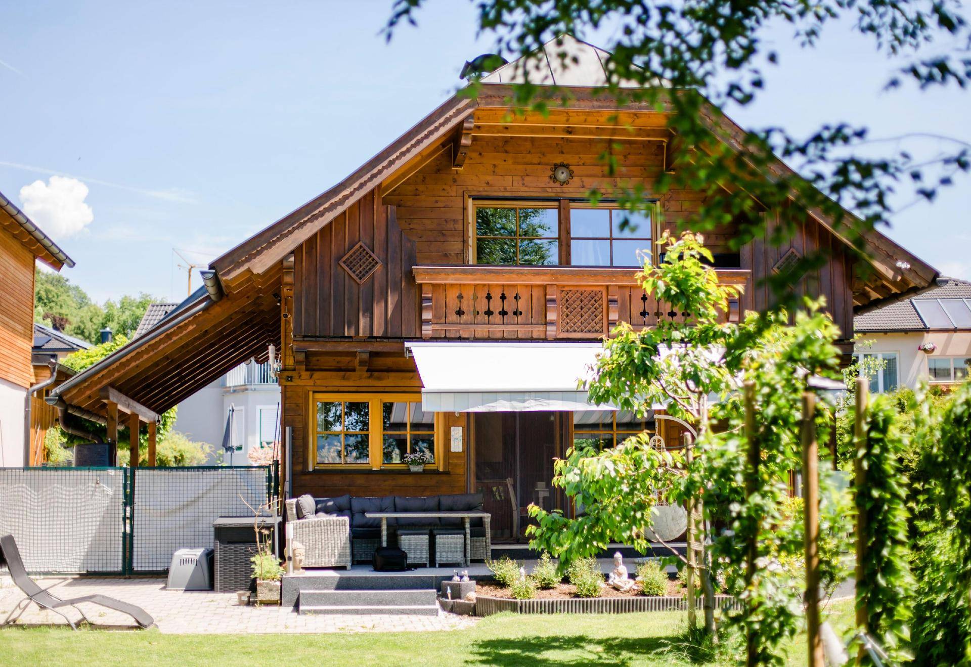 Charmantes Holzhaus mit traditioneller Architektur, umgeben von einem gepflegten Garten und einer Terrasse.