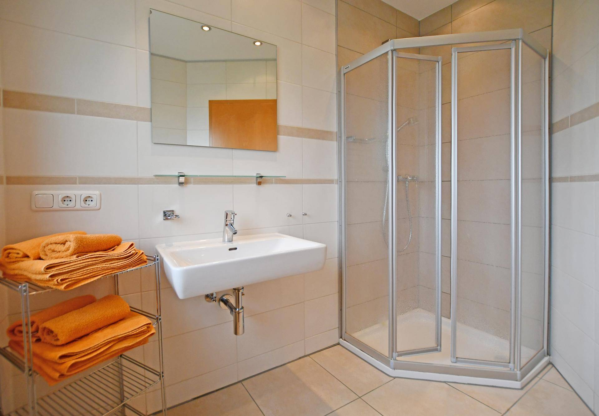 Helles Badezimmer mit Eckdusche, Einzelwaschbecken und beigen Fliesen.