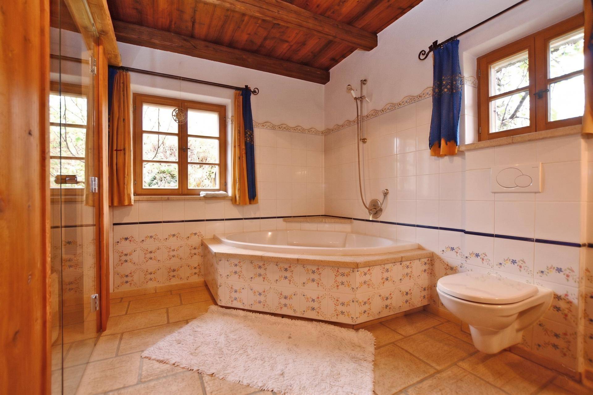 Helles Badezimmer mit Eckbadewanne, Wand-WC und traditionellen Fliesen in floralem Muster.