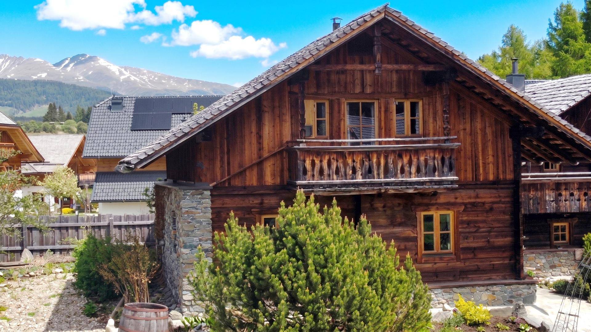 Alpines Holzchalet mit geschnitztem Balkon und beeindruckendem Blick auf schneebedeckte Berge.