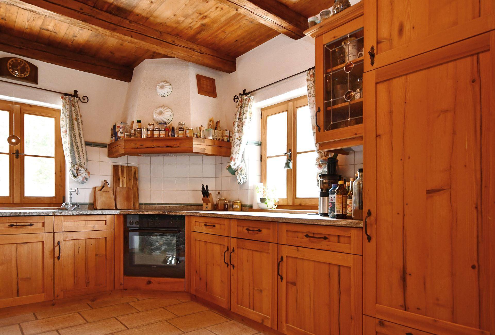 Rustikale Holzküche mit Einbaugeräten, gefliestem Spritzschutz und traditionellen Holzschränken.