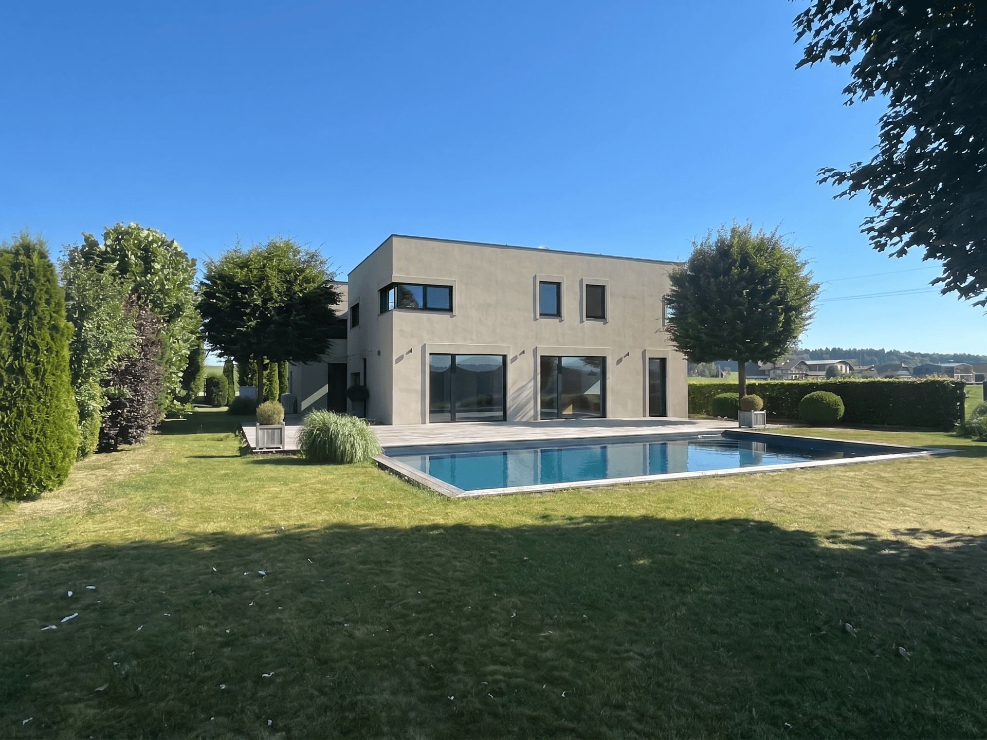 Elegantes modernes Haus mit großzügigem Garten, privatem Pool und gepflegter Rasenfläche.