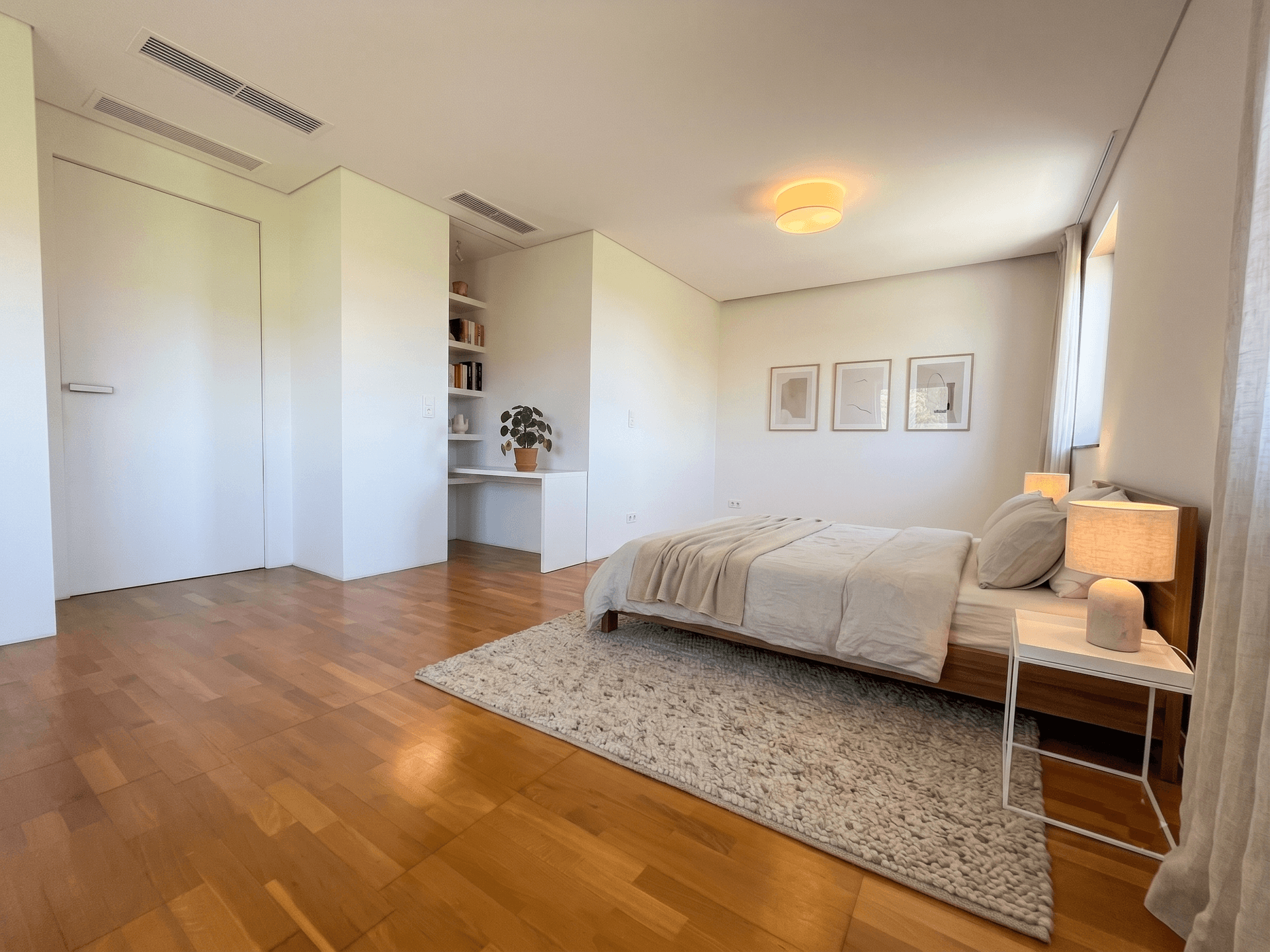 Geräumiges Schlafzimmer mit hellem Holzfußboden, minimalistischer Einrichtung und integrierten Regalen.
