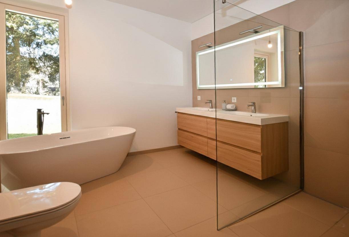 Elegantes Badezimmer mit freistehender Badewanne, Doppelwaschbecken und großer begehbarer Dusche.