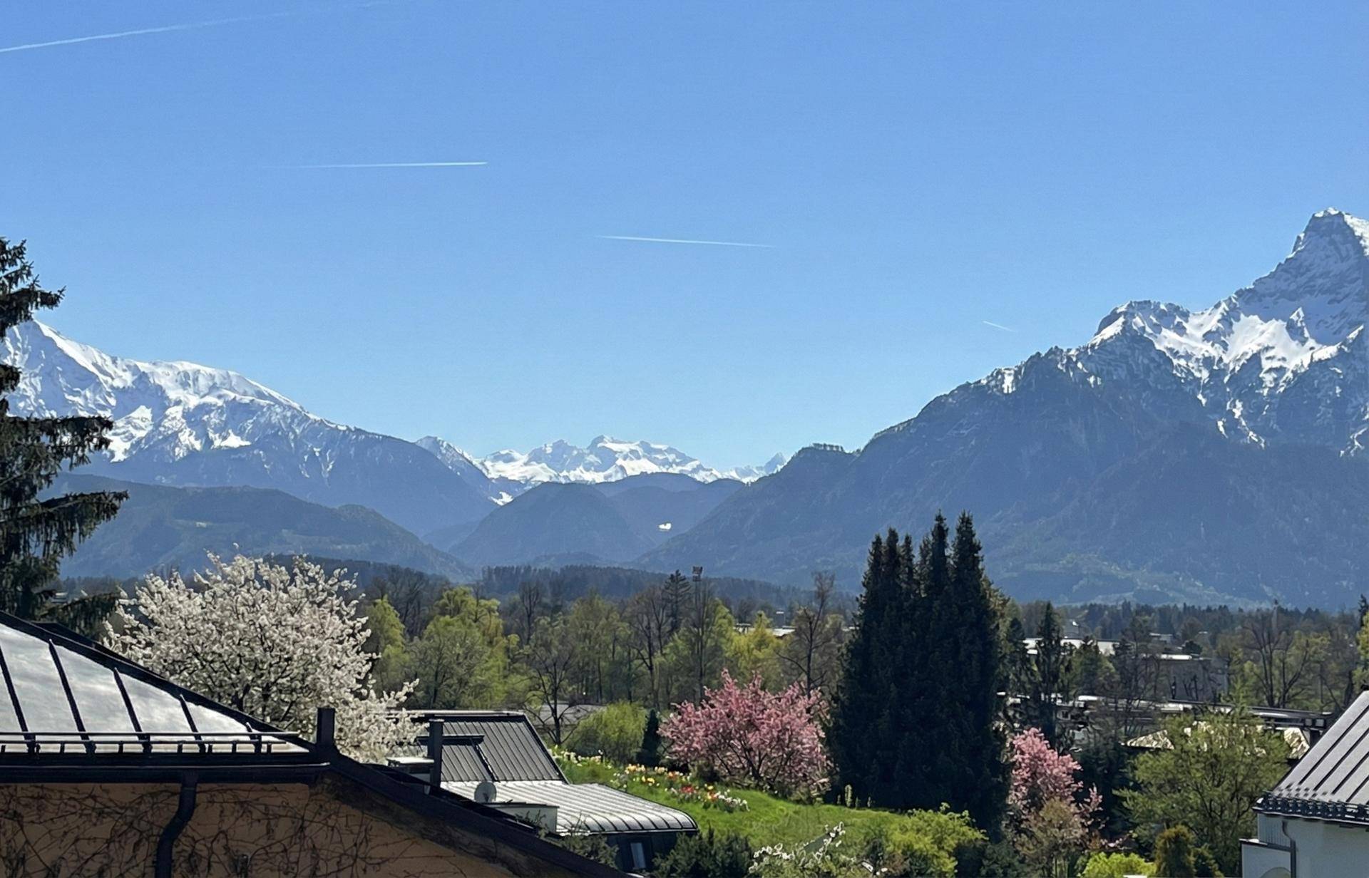 Atemberaubender Panoramablick auf die schneebedeckten Berge und die grüne Landschaft unter blauem Himmel.