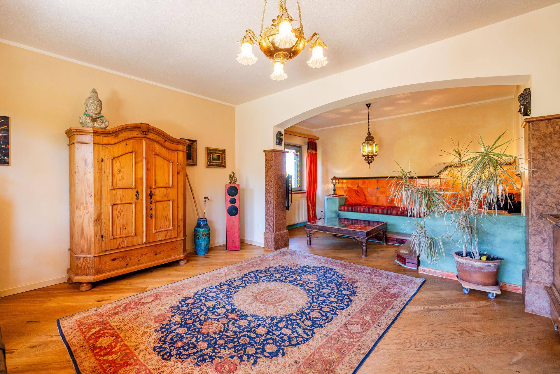 Geräumiges Wohnzimmer mit Holzboden, traditionellem Teppich und einem gemütlichen Sitzbereich.
