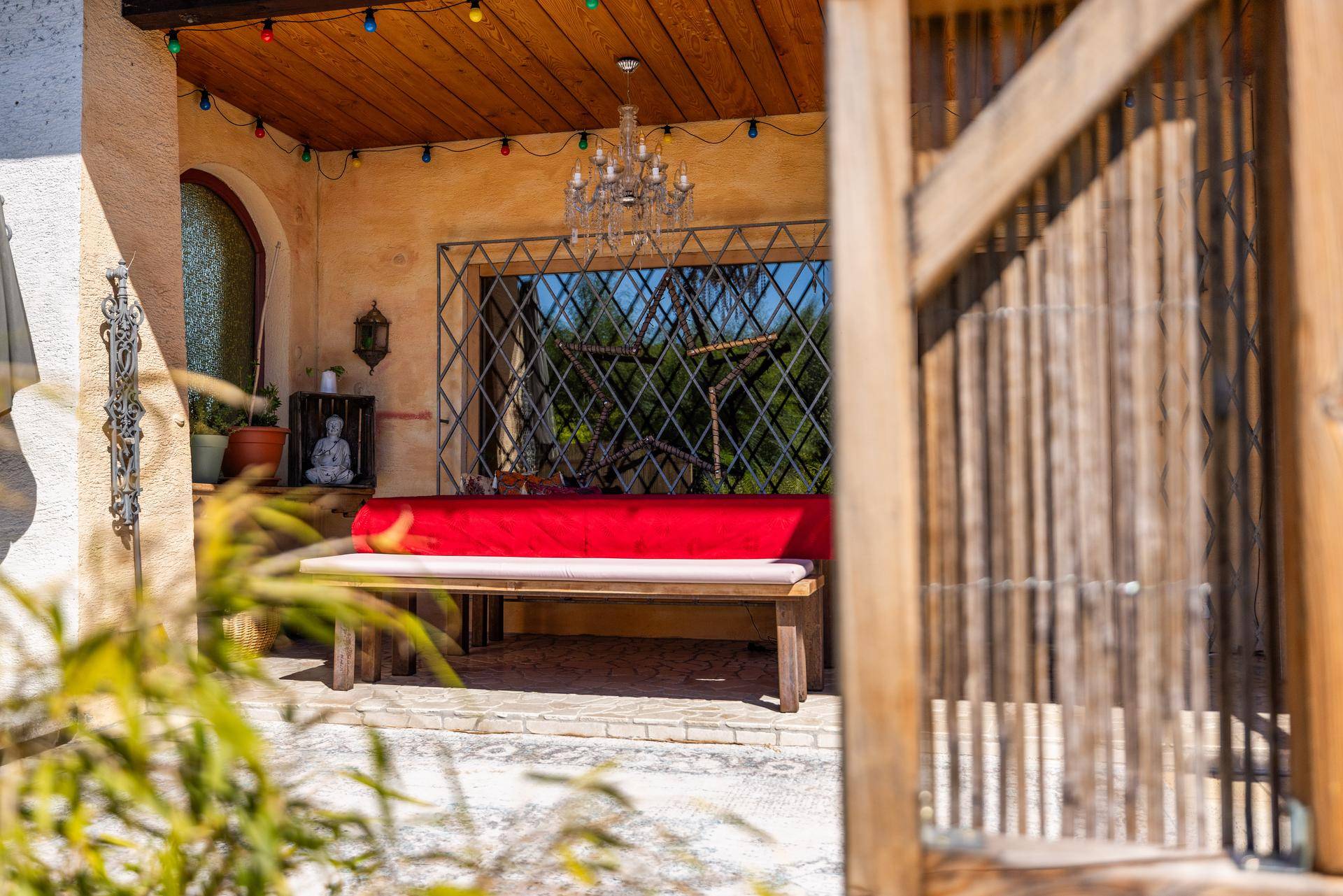 Gemütliche überdachte Terrasse mit Holzbänken und stimmungsvoller Beleuchtung für entspannte Stunden im Freien.