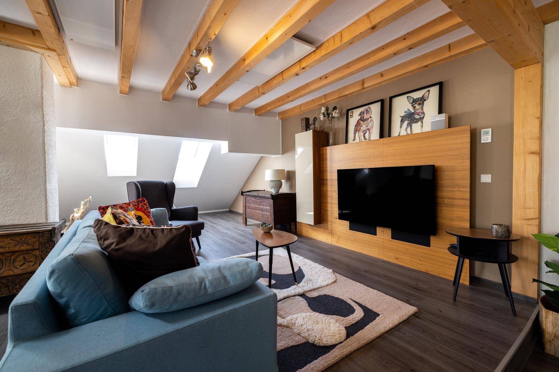 Heller Wohnbereich mit modernem TV-Möbel, bequemer Couch und Dachfenstern für viel Tageslicht.