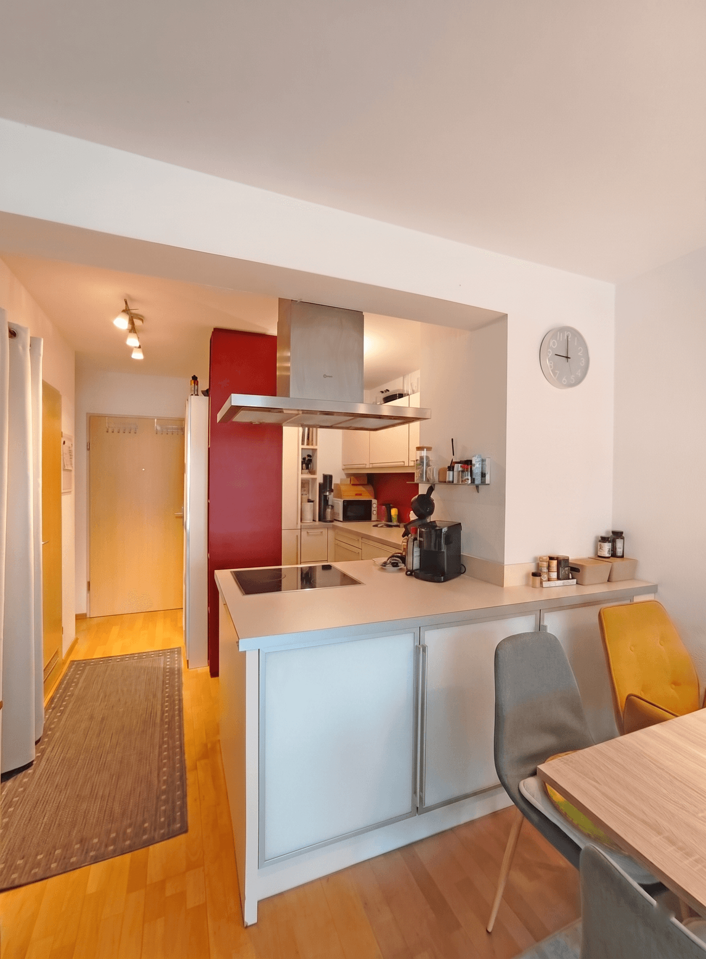Moderne, halboffene Küche mit Induktionskochfeld, Dunstabzugshaube und Essbereich.