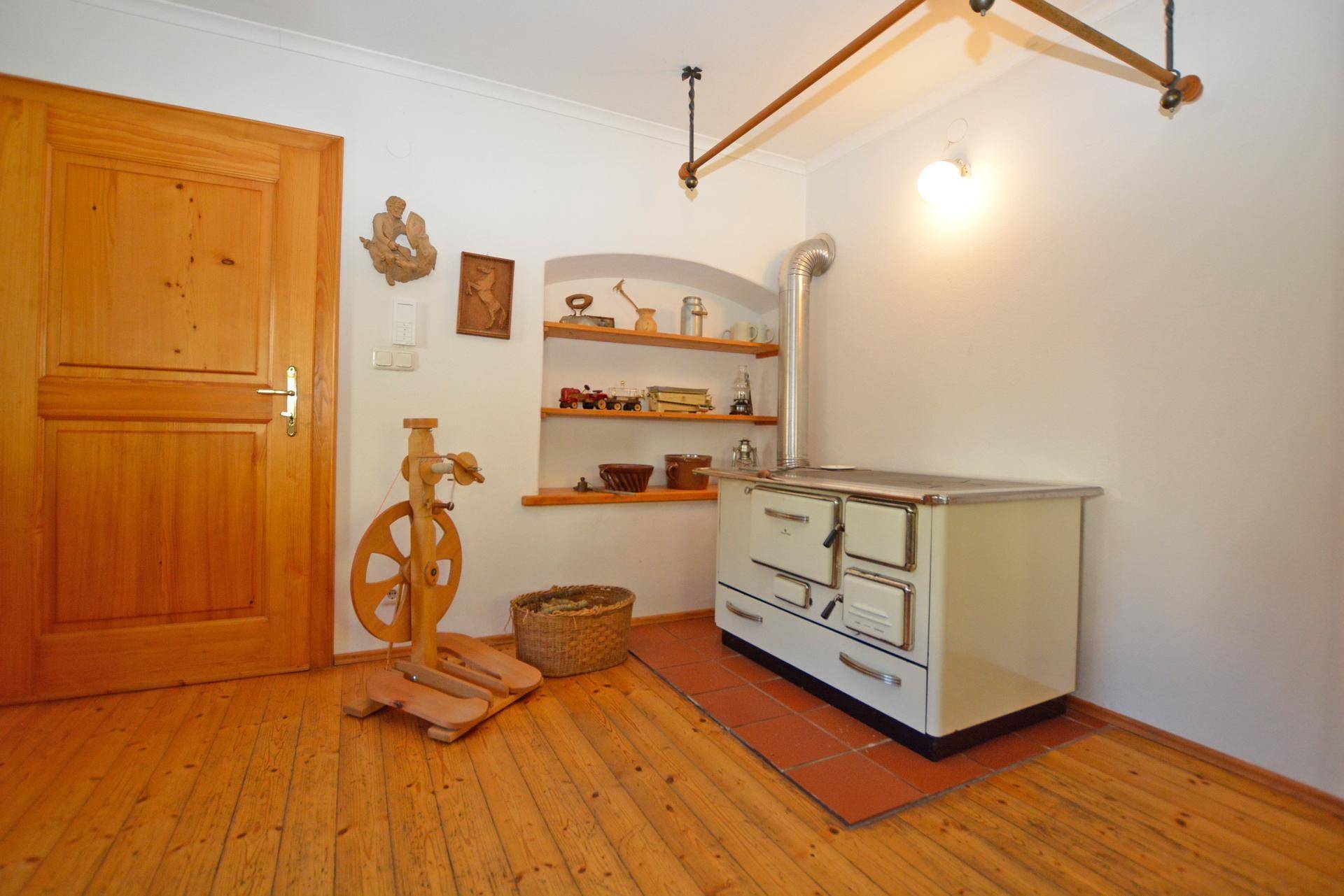 Rustikaler Raum mit traditionellem Holzofen, Holzboden und Holztür, im Landhausstil eingerichtet.