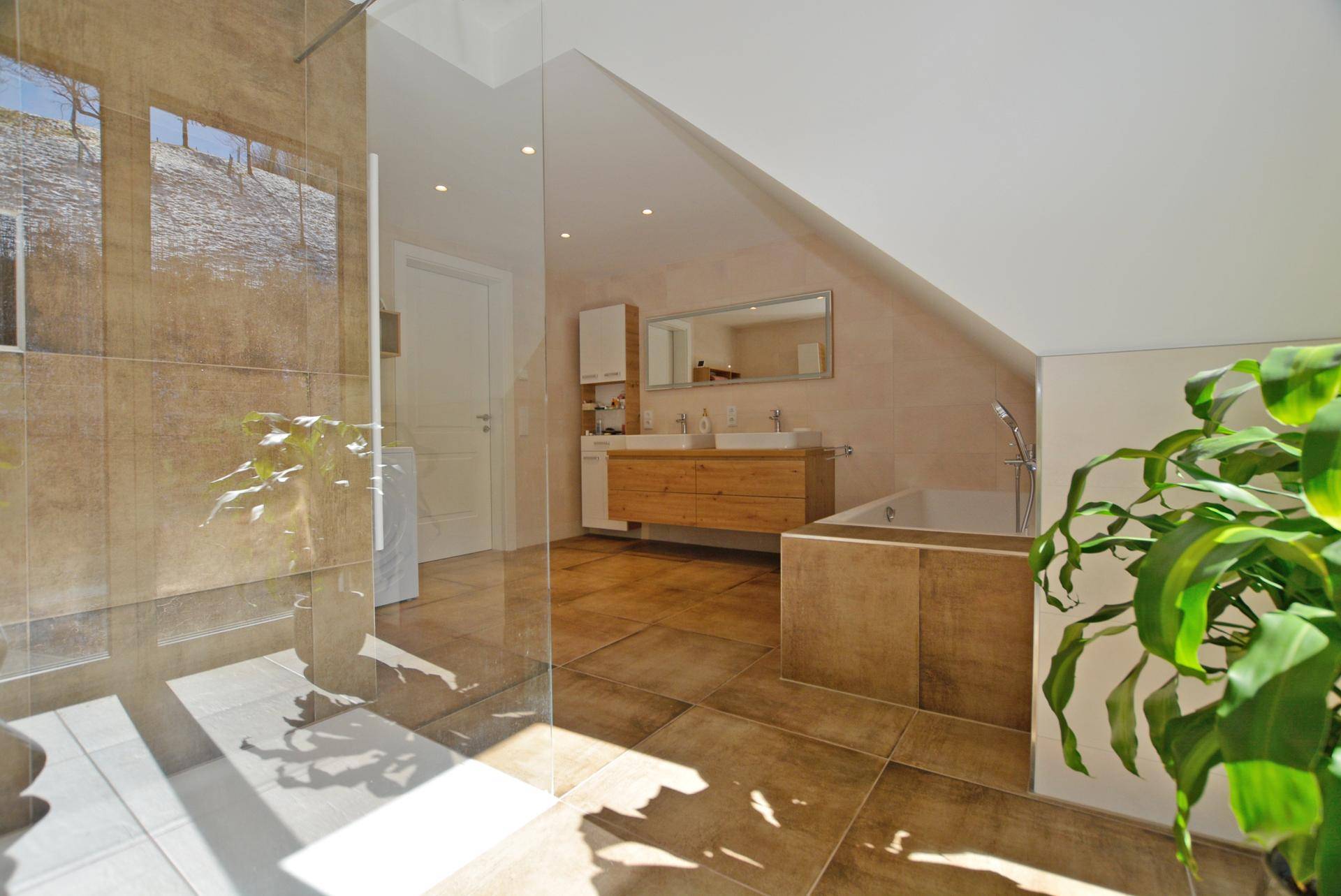 Modernes Badezimmer mit begehbarer Dusche, Doppelwaschbecken und großen Fliesen, hell und geräumig.