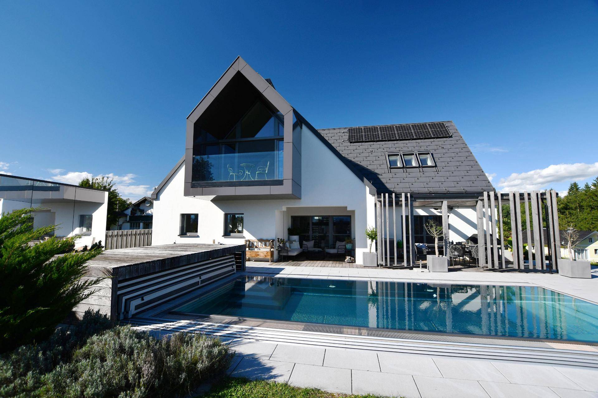 Architektonisch ansprechendes Haus mit großem Pool und moderner Fassadengestaltung.