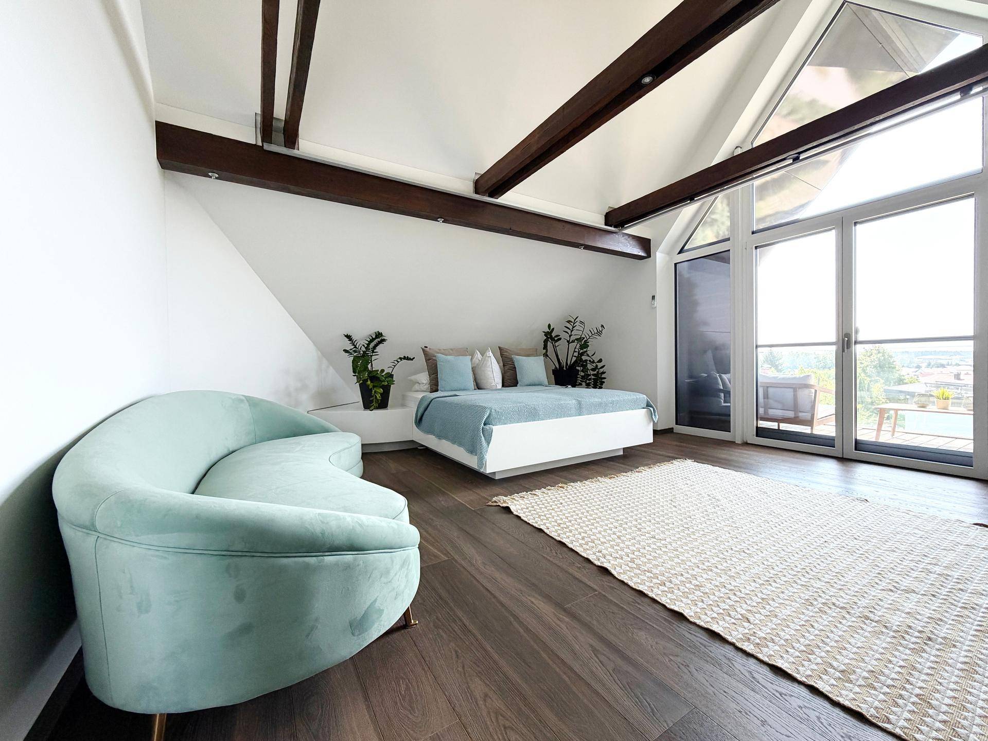 Geräumiges Schlafzimmer mit hohen Decken, Holzbalken und Zugang zur Terrasse.