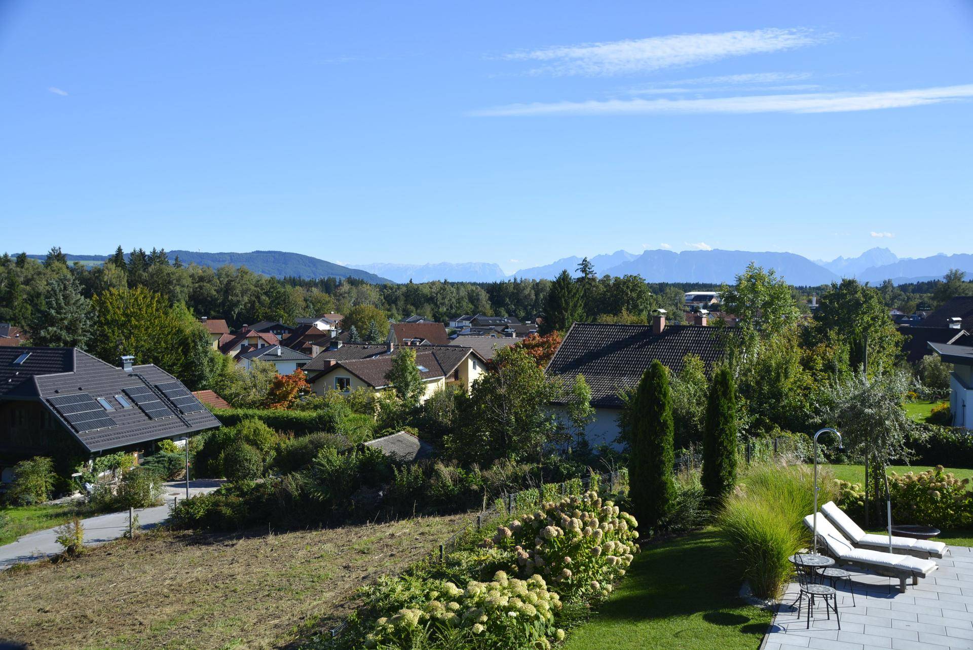 Weitläufiger Blick über die Nachbarschaft mit grünen Hügeln und Bergen im Hintergrund.
