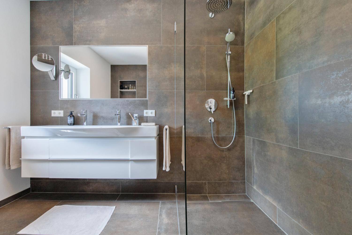 Elegantes Badezimmer mit Doppelwaschbecken, großer Dusche und modernen Fliesen.