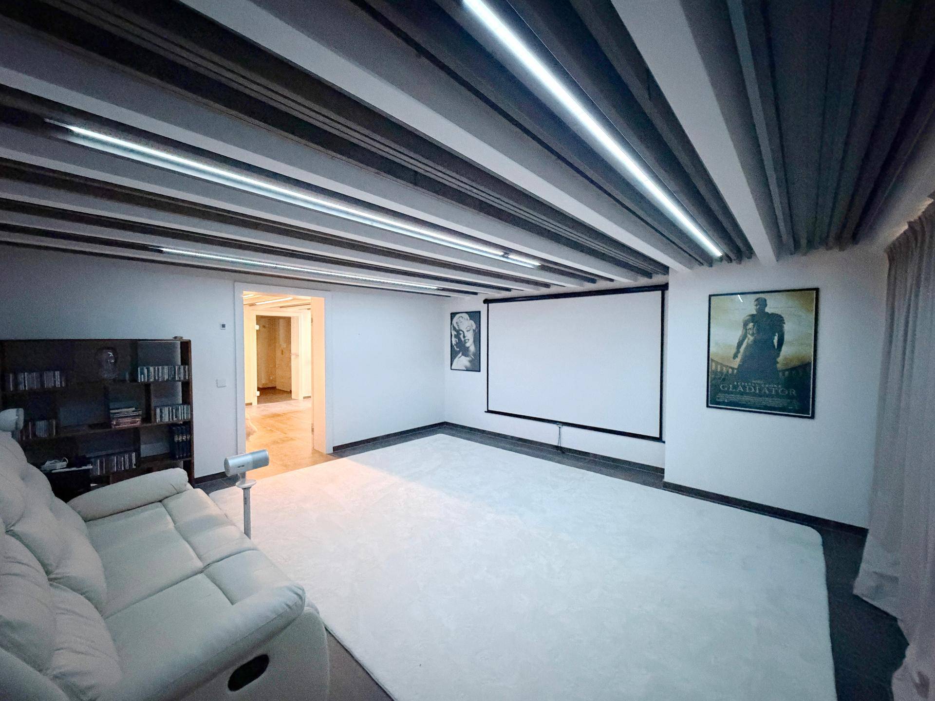 Gemütlicher Medienraum mit großer Leinwand, Sofa und indirekter Beleuchtung.
