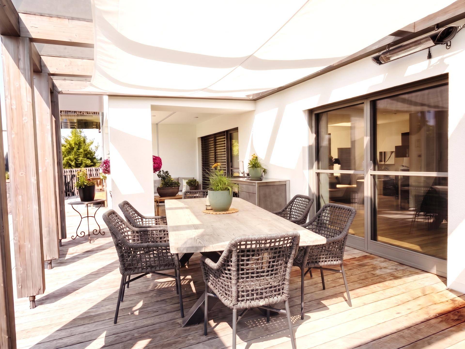 Große Holzterrasse mit Esstisch und Stühlen, ideal für Mahlzeiten im Freien.