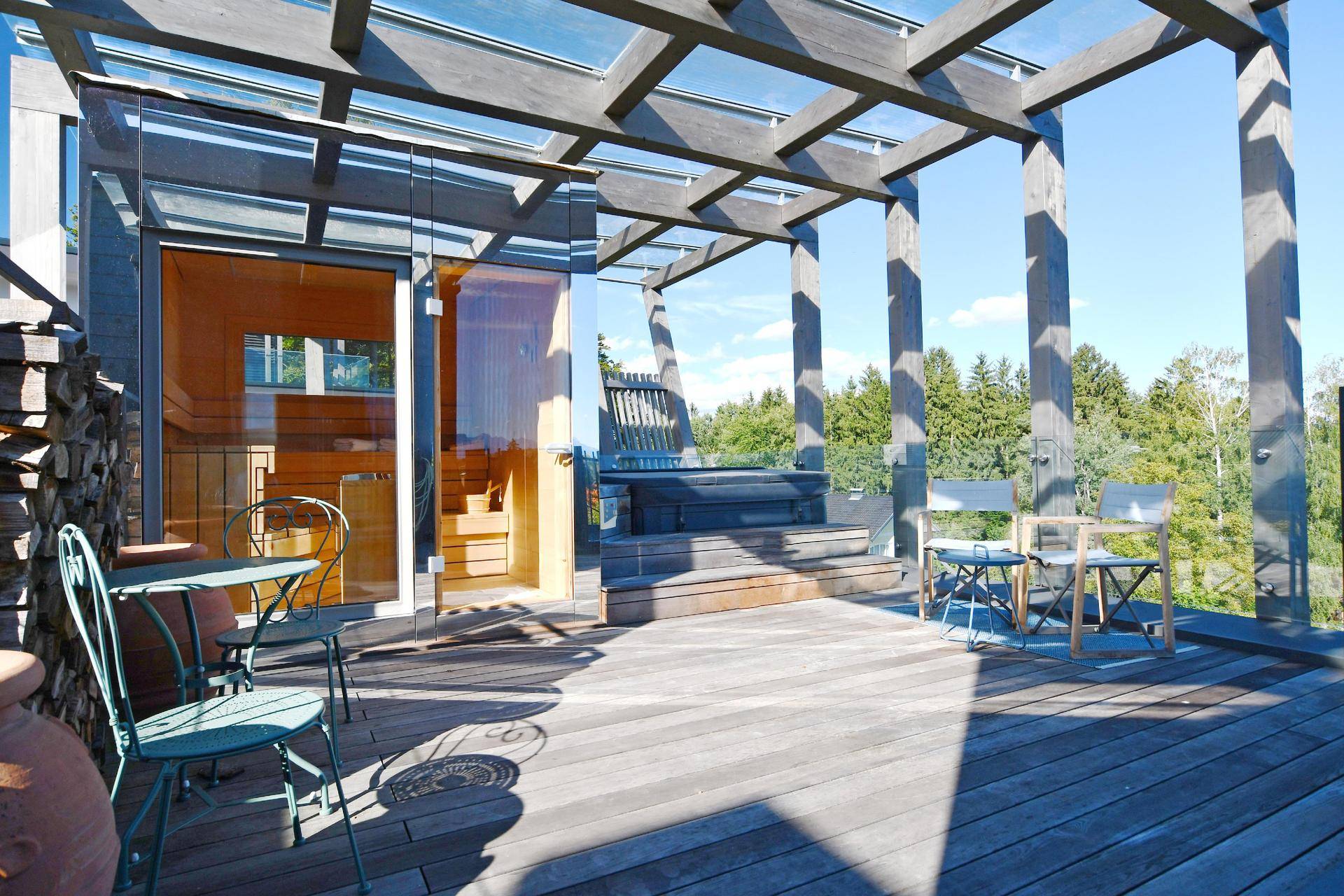 Geräumige Holzterrasse mit Whirlpool, Sauna und Sitzgelegenheiten im Freien.