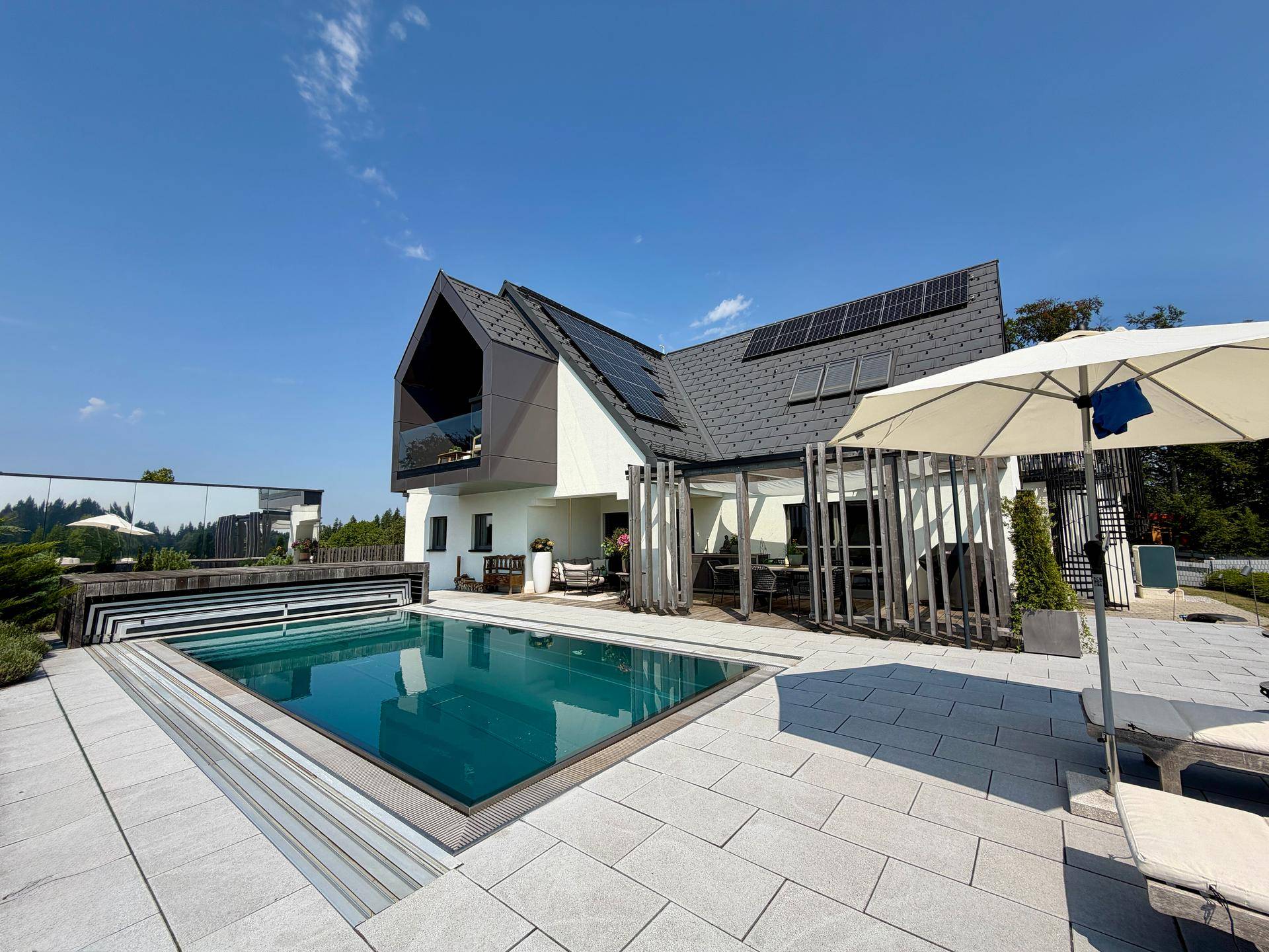 Modernes Haus mit Pool, Photovoltaikanlage auf dem Dach und großzügiger Terrasse.