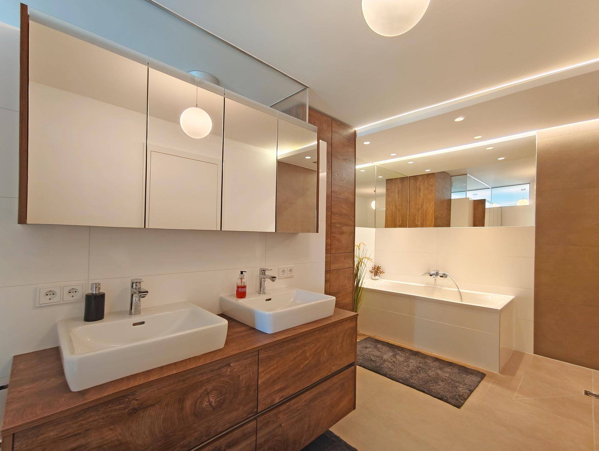 Modernes Badezimmer mit Doppelwaschbecken, großen Spiegelschränken, Badewanne und stilvollen Fliesen.
