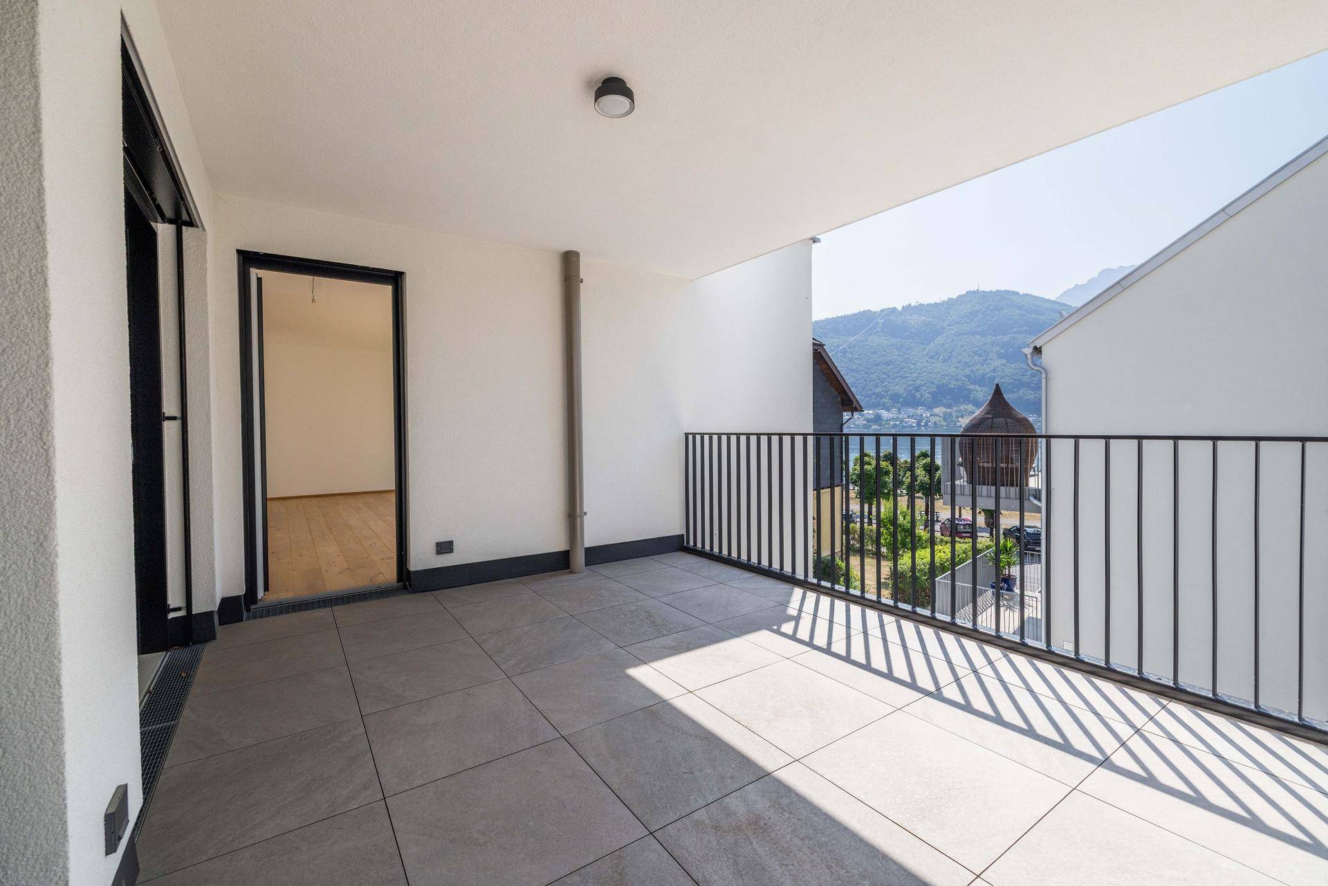 Geräumiger Balkon mit Fliesenboden und Blick auf die umliegende Berglandschaft.