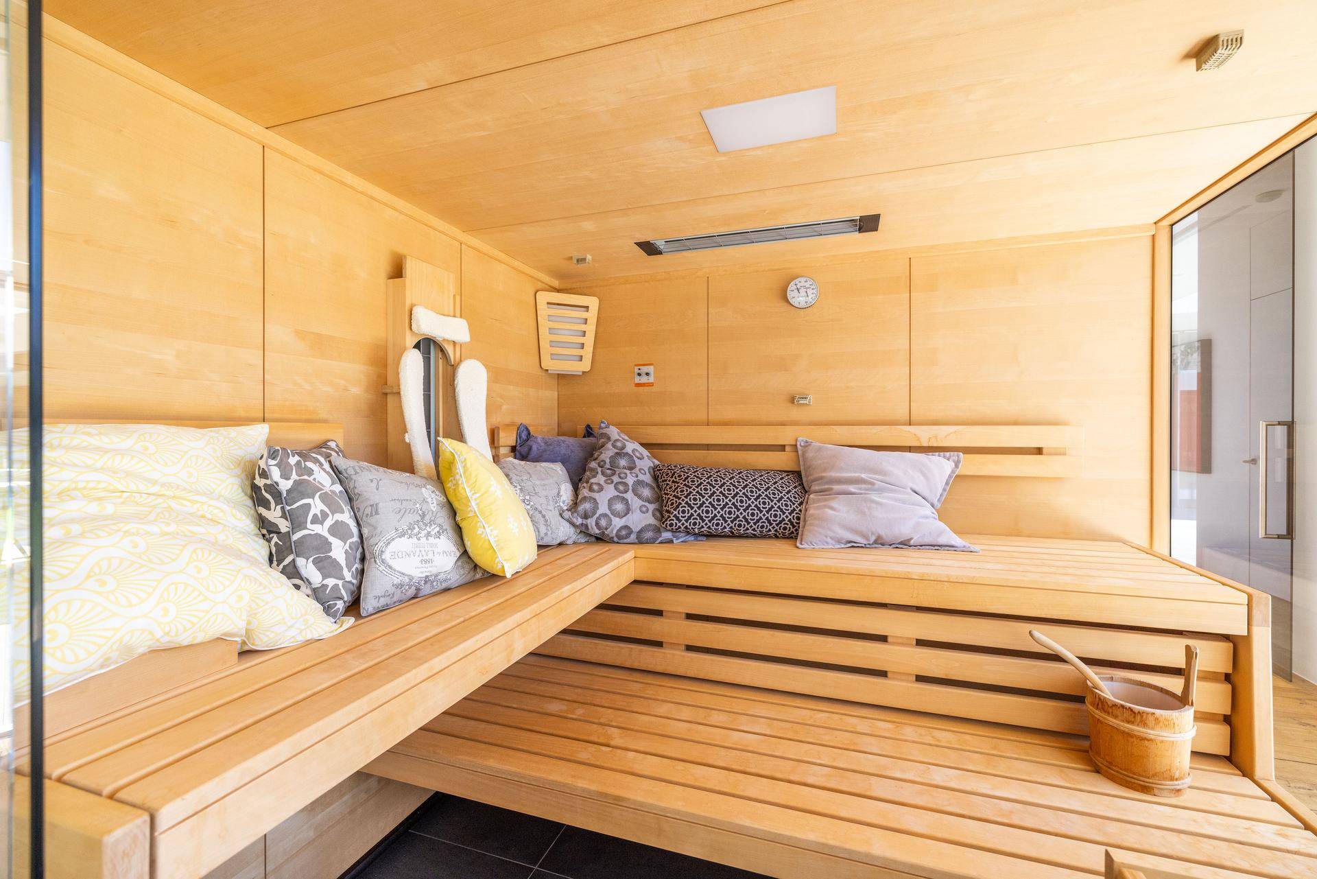 Gemütliche Holzsauna mit bequemen Bänken und Kissen für entspannende Momente.