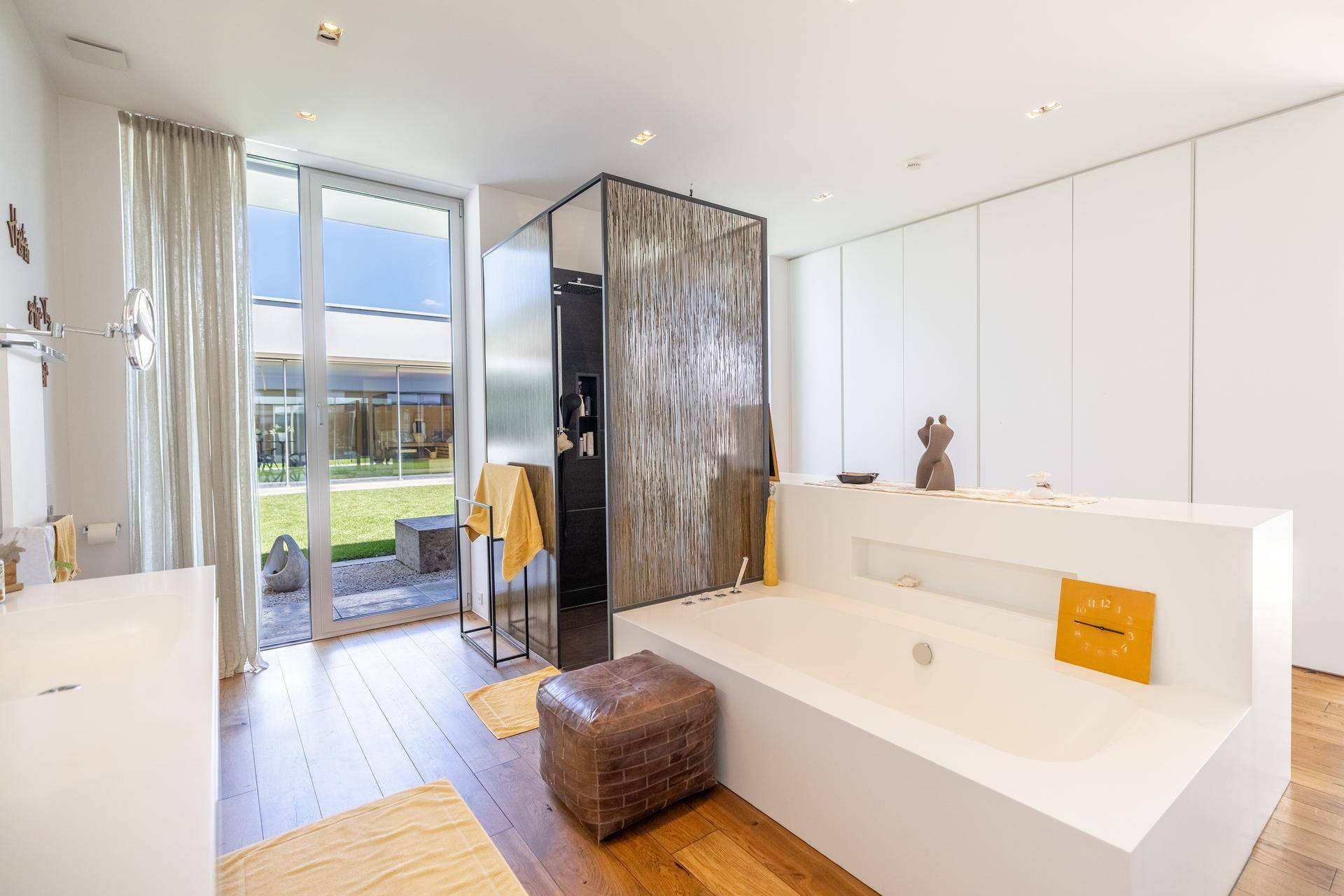 Modernes Badezimmer mit Badewanne, Doppelwaschbecken und Zugang zu einem kleinen Gartenbereich.