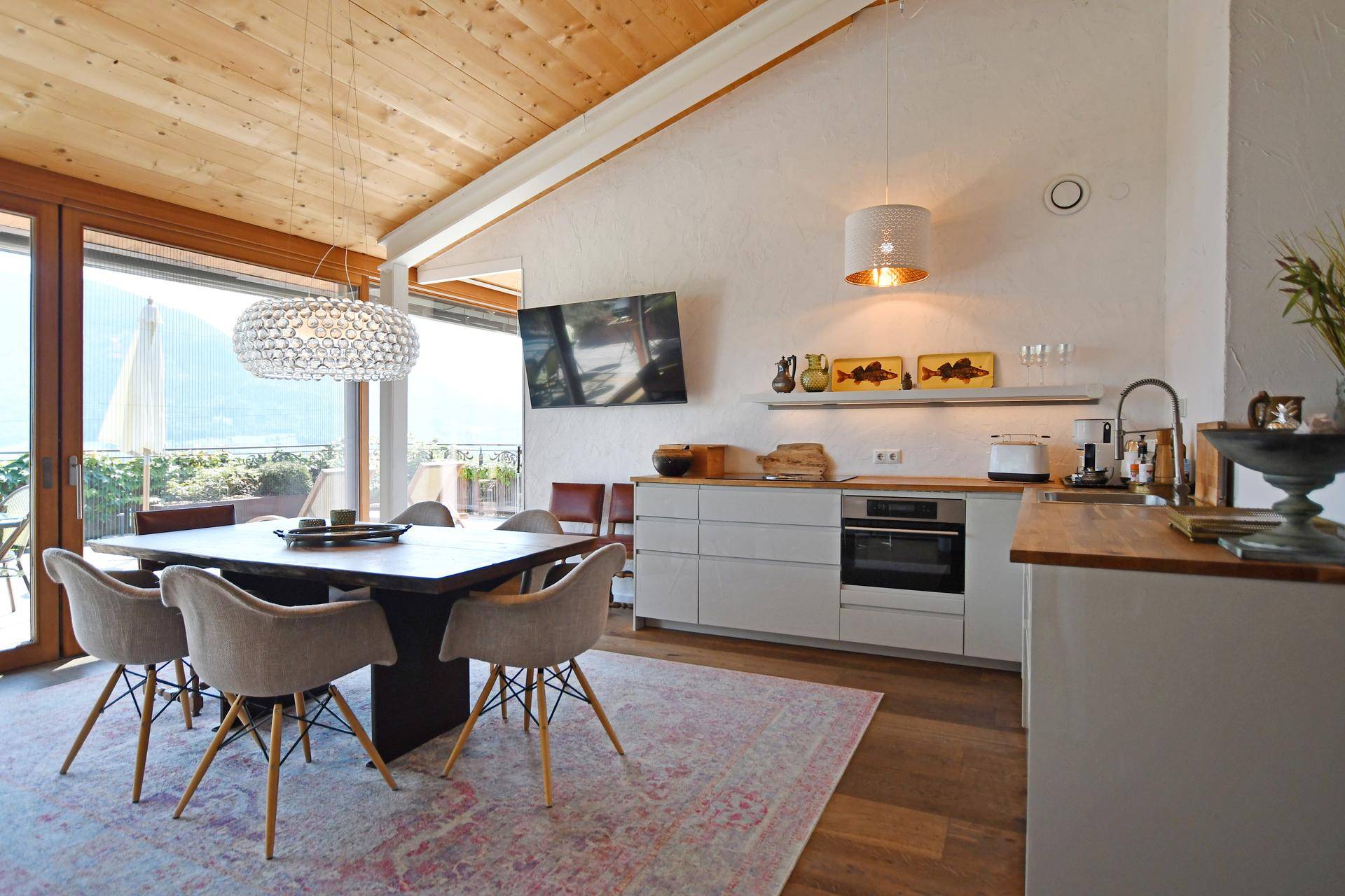 Offener Wohn-Essbereich mit moderner Küche, Holzboden und Zugang zur Terrasse.