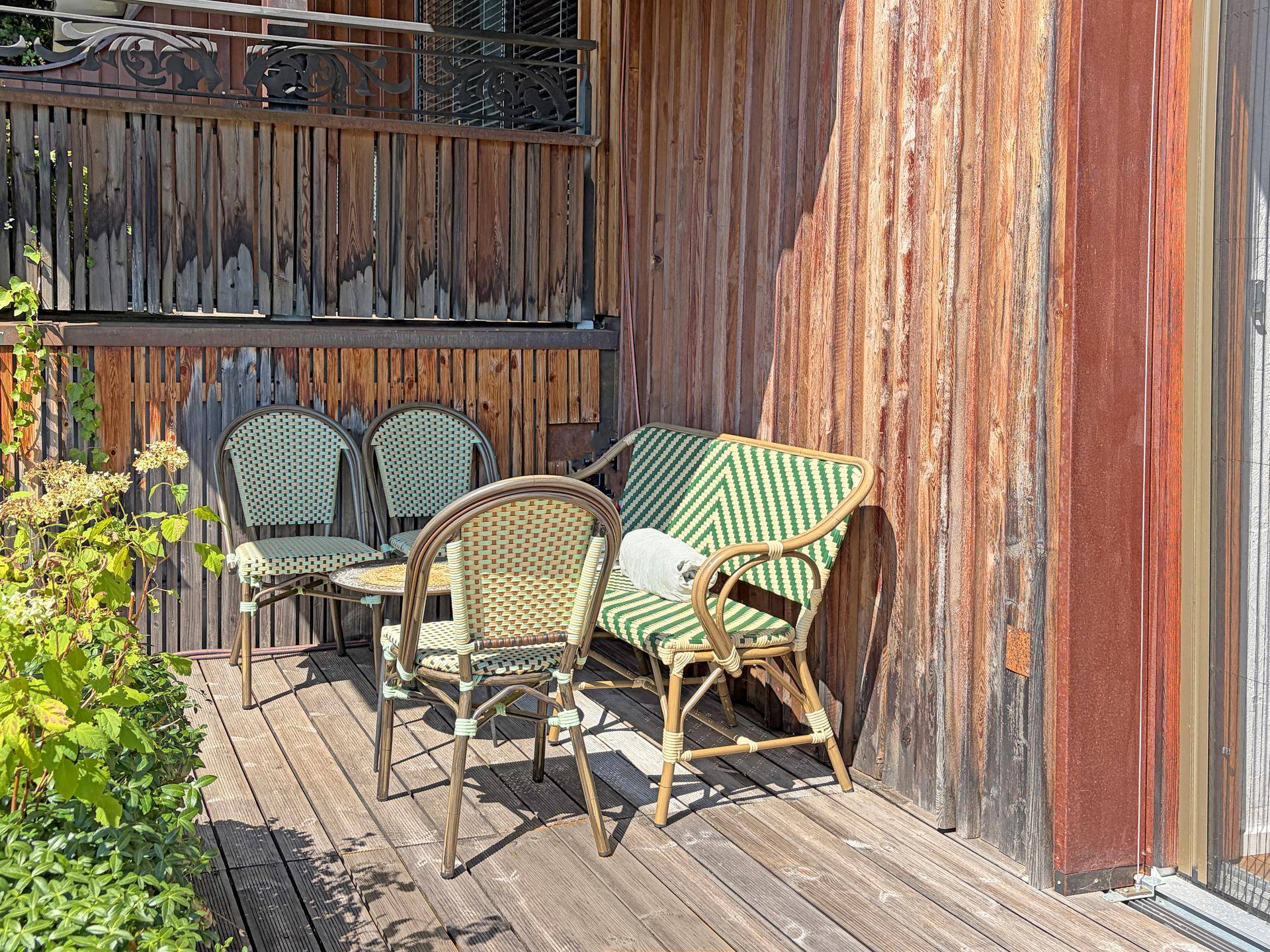 Kleine, gemütliche Terrasse mit Sitzgelegenheiten und Holzwänden, ideal zum Entspannen.