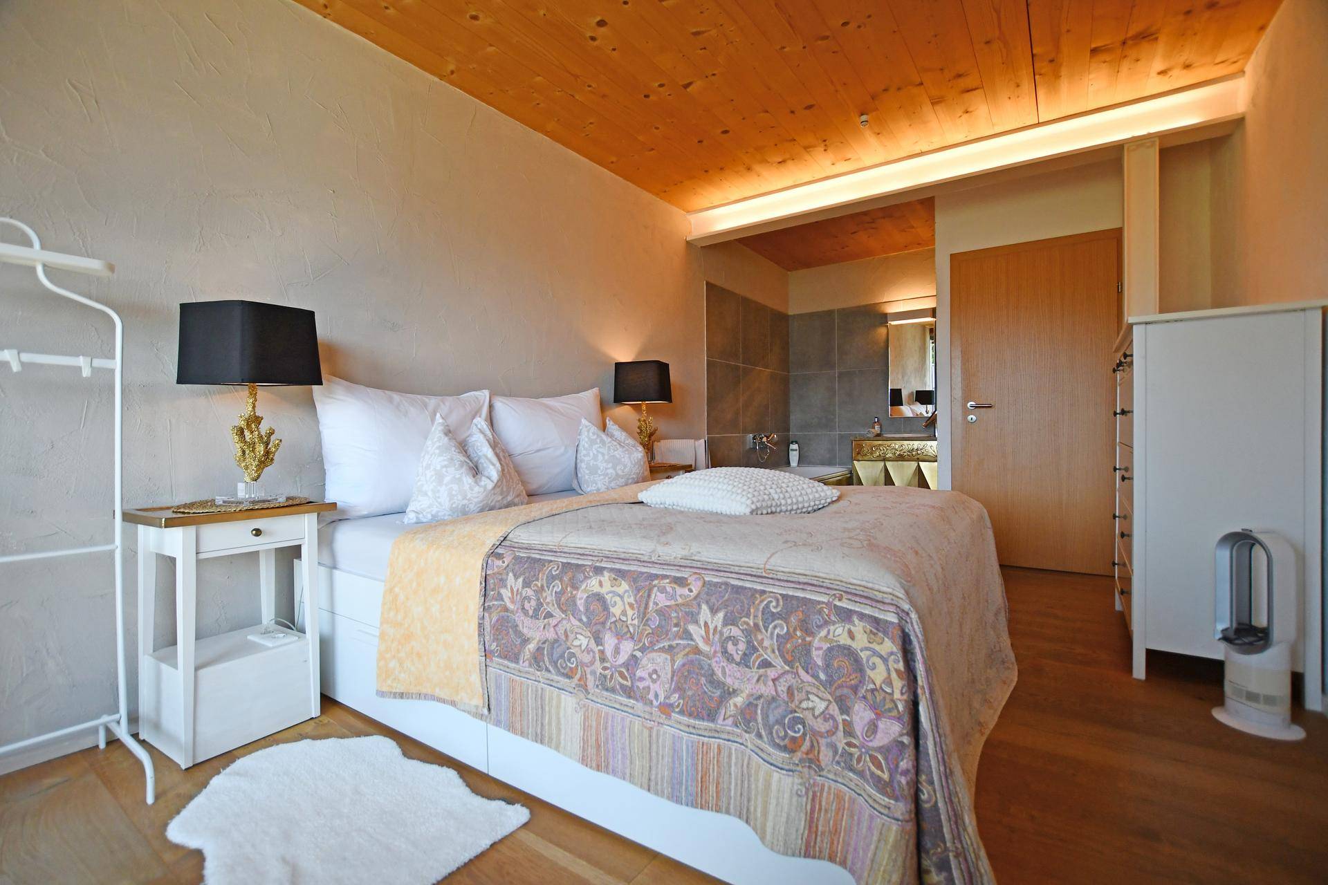 Komfortables Schlafzimmer mit Holzboden und direktem Zugang zu einem angrenzenden Badezimmer.