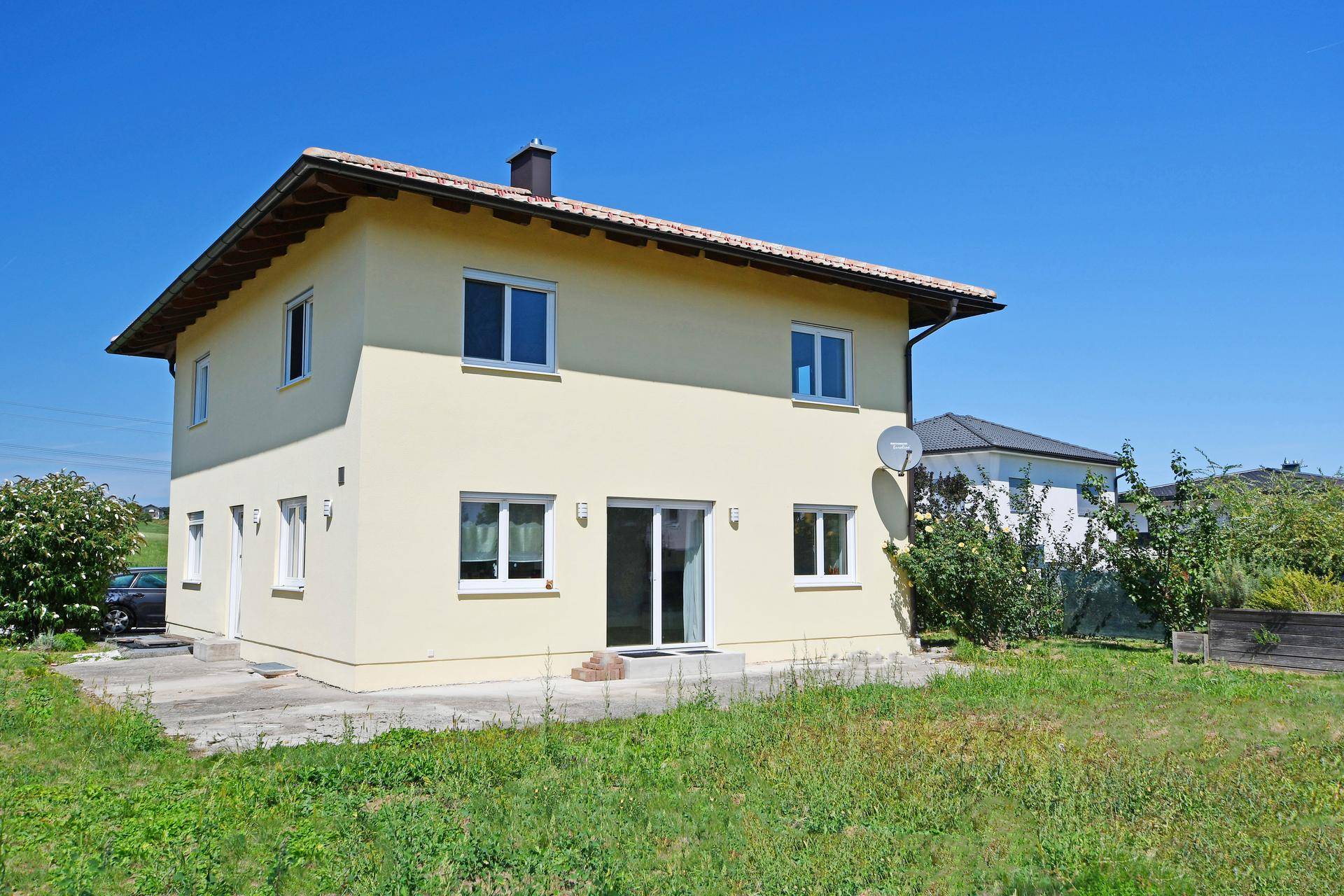 Rückansicht des Einfamilienhauses mit Terrasse und weitem Blick ins Grüne.
