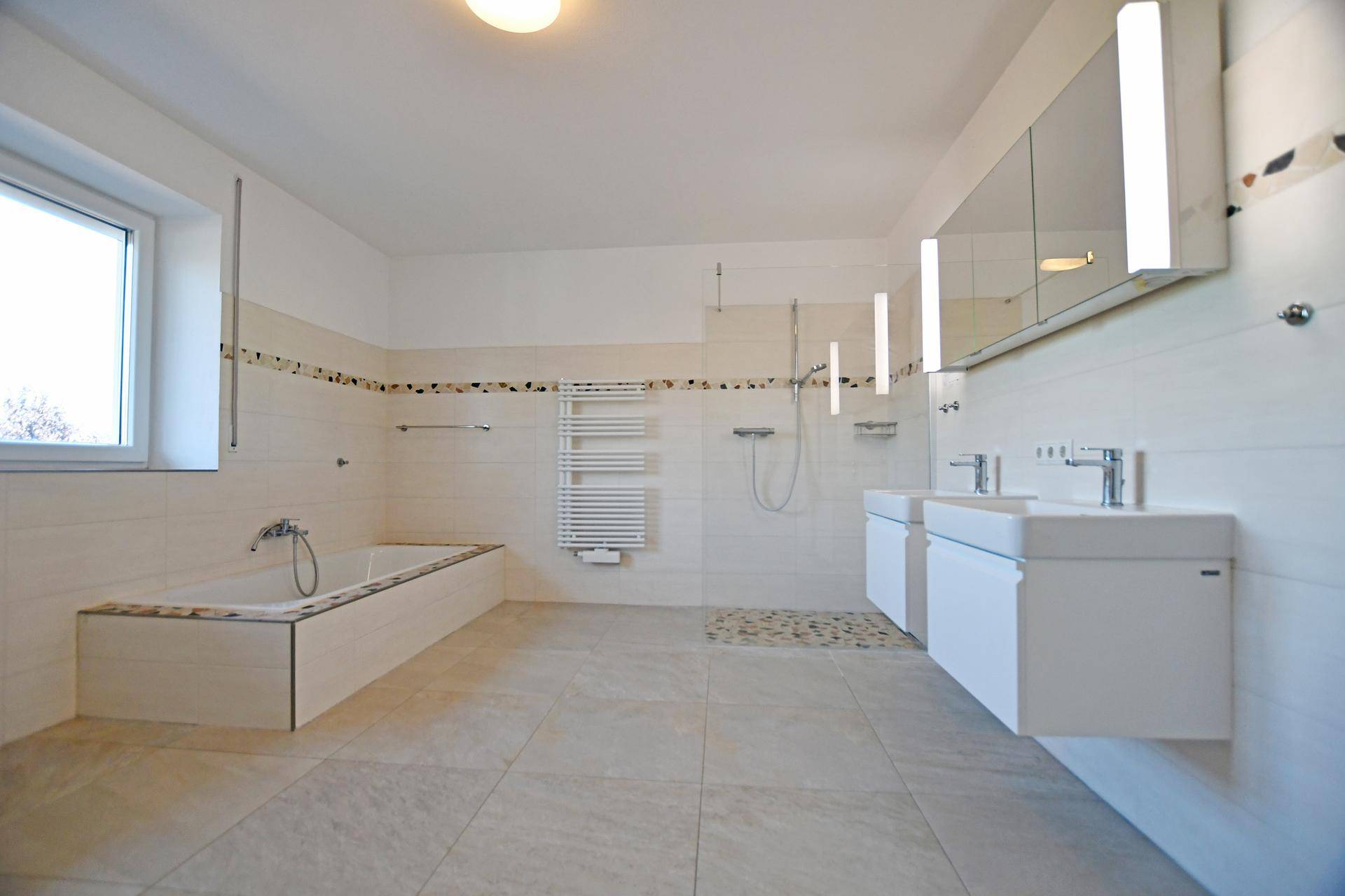 Geräumiges Badezimmer mit Doppelwaschbecken, Badewanne und großer Dusche.
