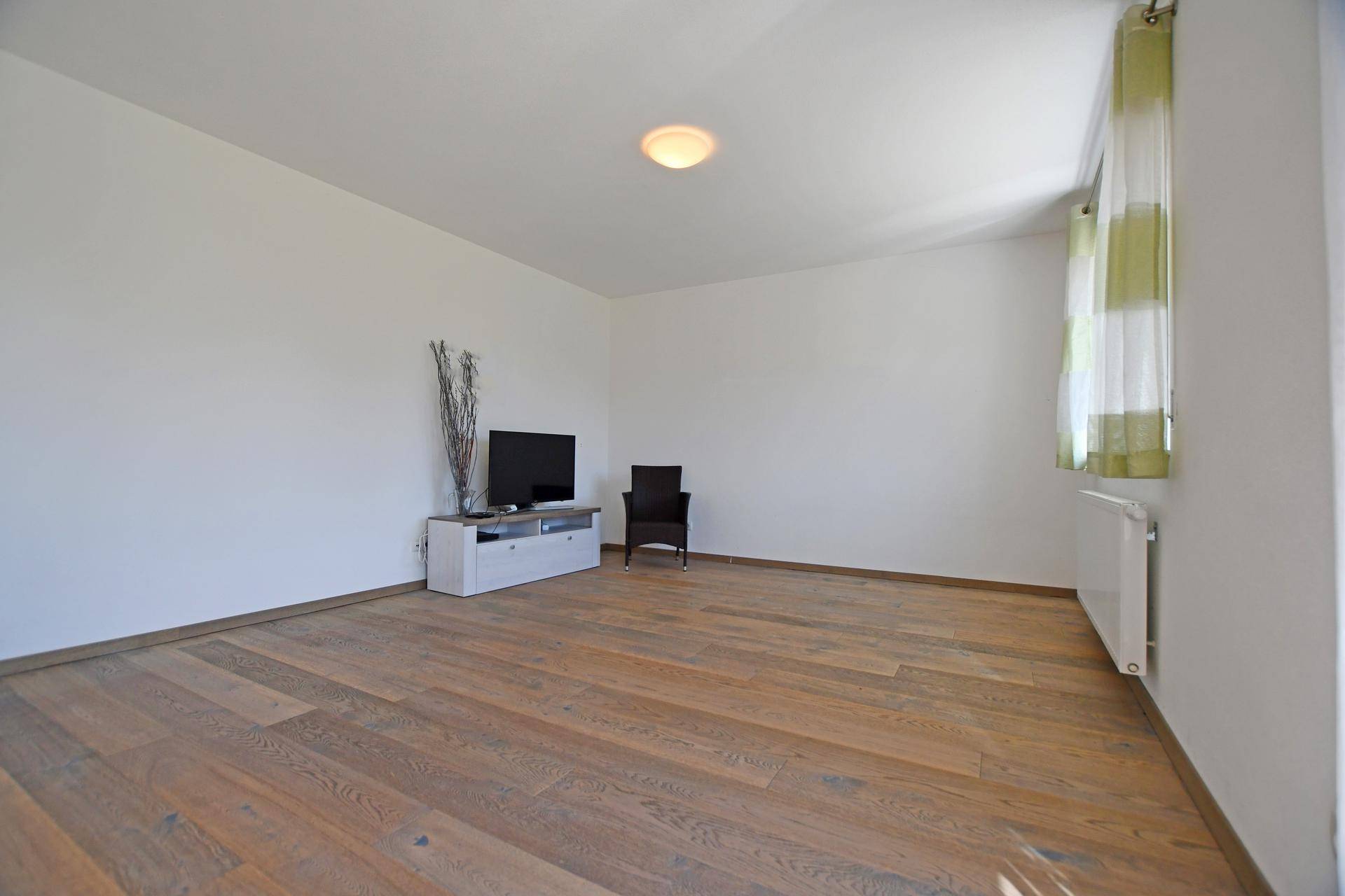 Helles Wohnzimmer mit modernem Holzboden und weiß gestrichenen Wänden.