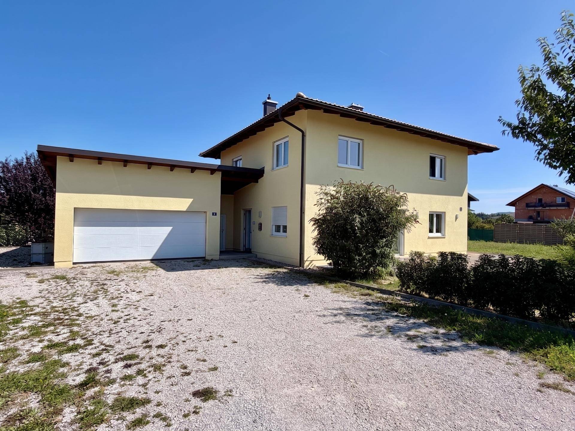 Einfamilienhaus mit integrierter Garage und großzügiger Kiesauffahrt.
