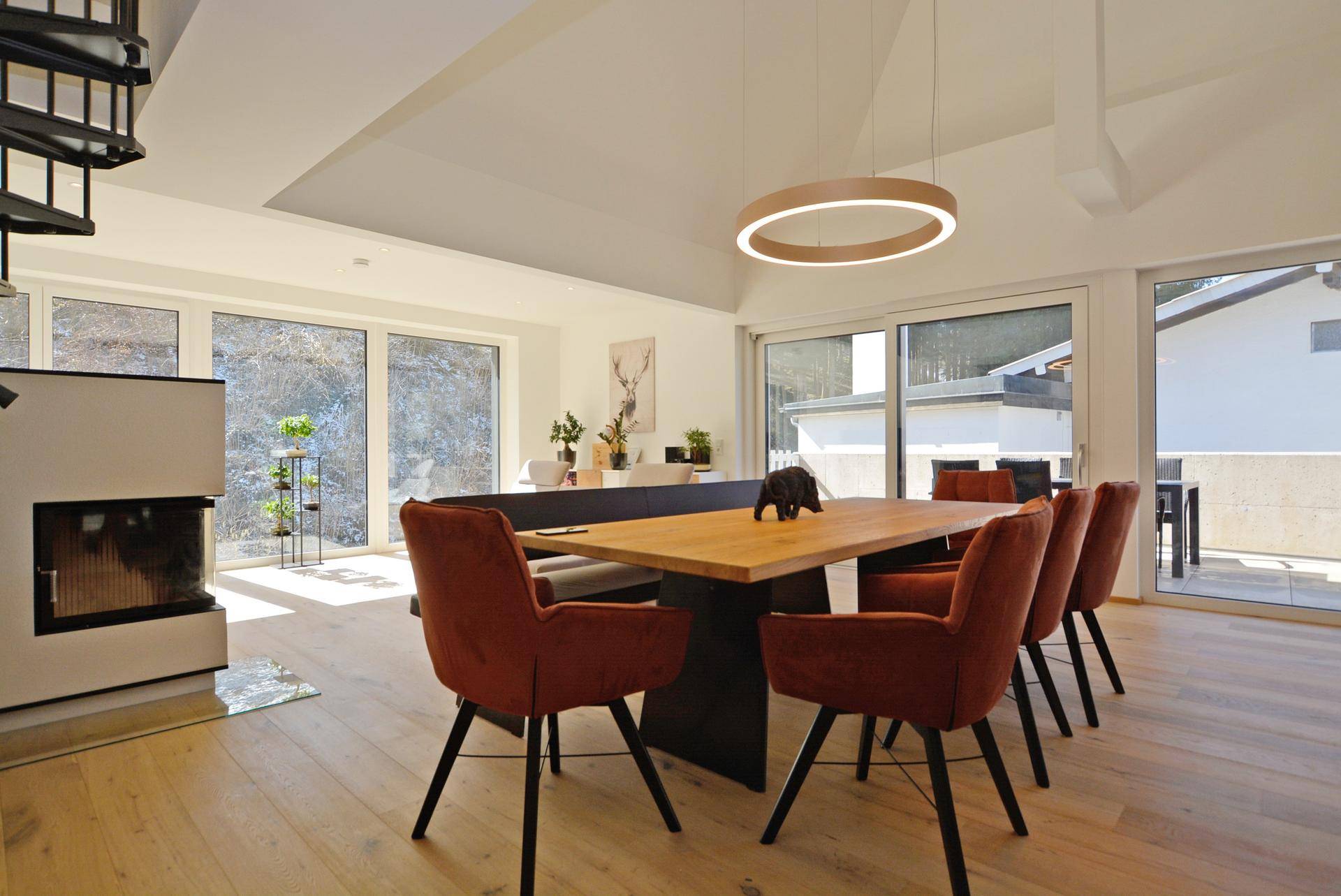Heller Essbereich mit großem Holztisch, modernen Stühlen und Kamin, mit Zugang zur Terrasse.