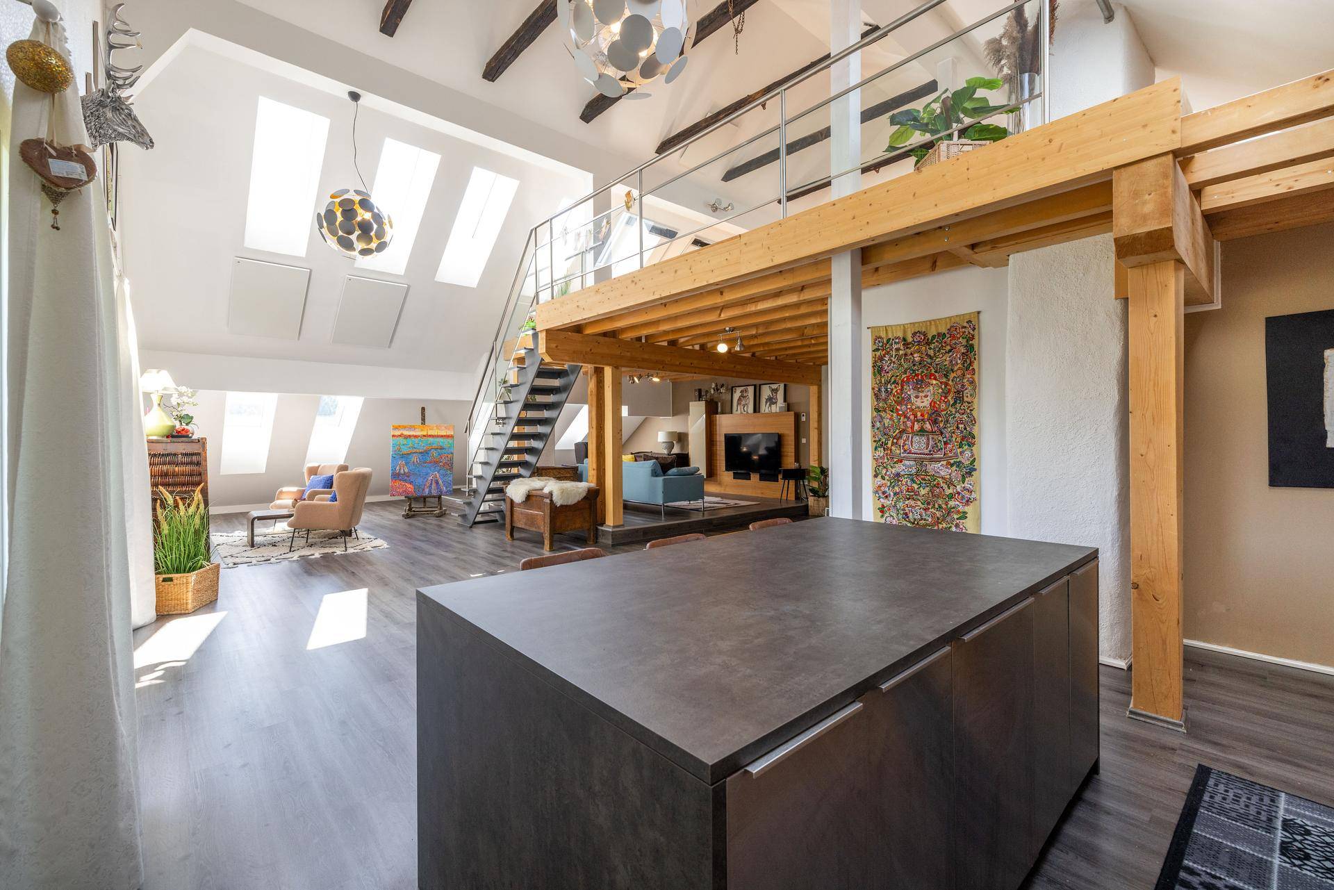 Geräumiger offener Wohnbereich im Loft-Stil mit hohen Decken, Holzbalken und viel Tageslicht.