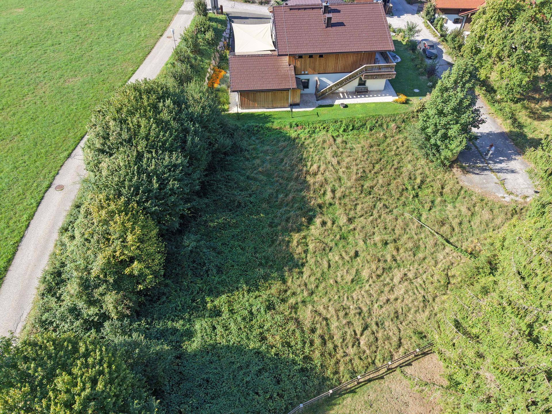 Übersicht des Grundstücks mit einem Haus, großer Grünfläche und angrenzender Straße.