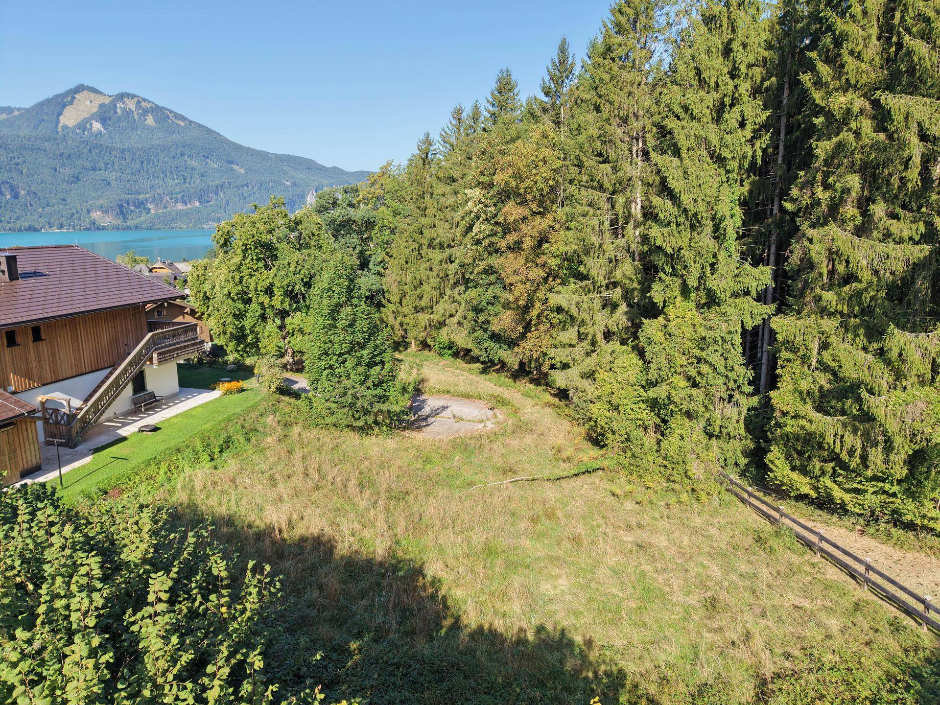 Luftaufnahme eines Grundstücks mit Haus, Wald und einem See im Hintergrund.