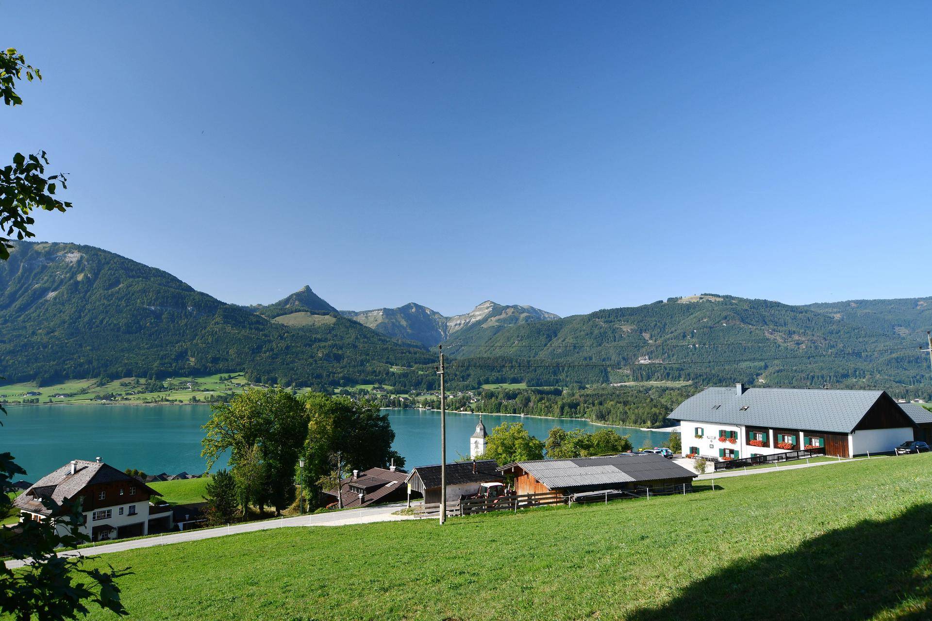 Malerischer Blick auf einen See und die umliegende Berglandschaft mit traditionellen Häusern.