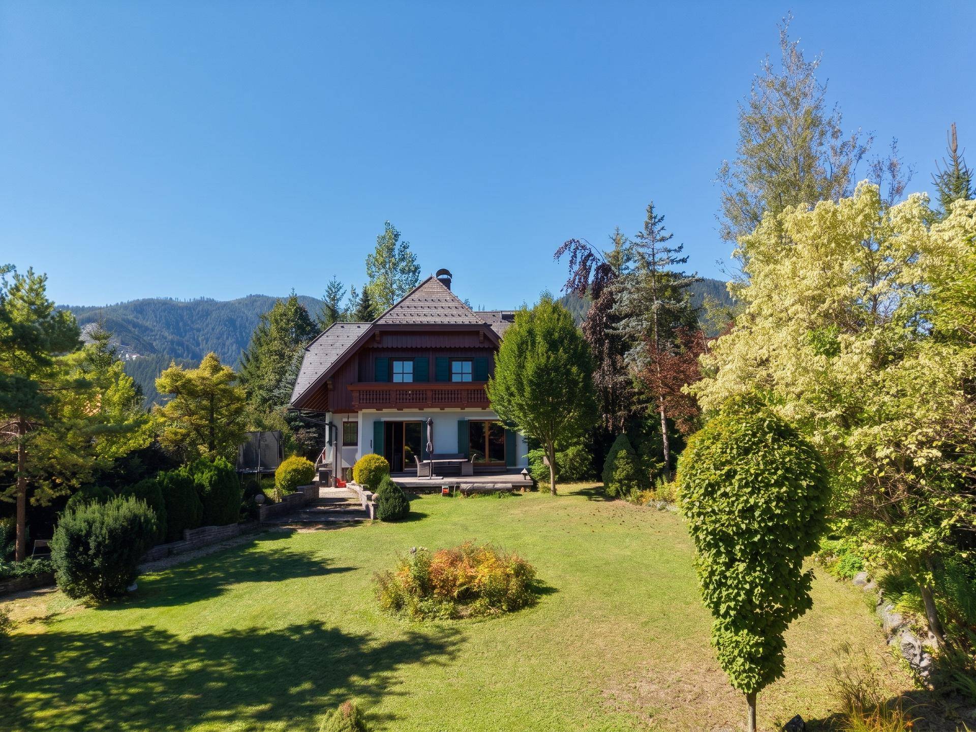 Charmantes Haus im Grünen mit Bergblick, umgeben von Bäumen und einem weitläufigen Garten.
