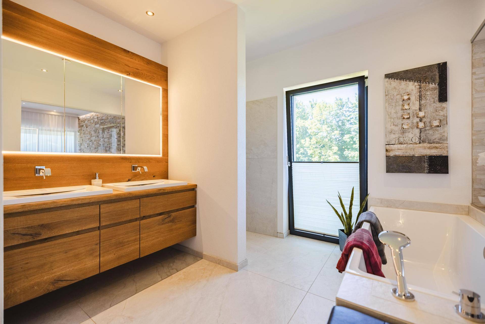 Modernes Badezimmer mit Doppelwaschbecken, beleuchtetem Spiegelschrank und Badewanne mit Fenster.