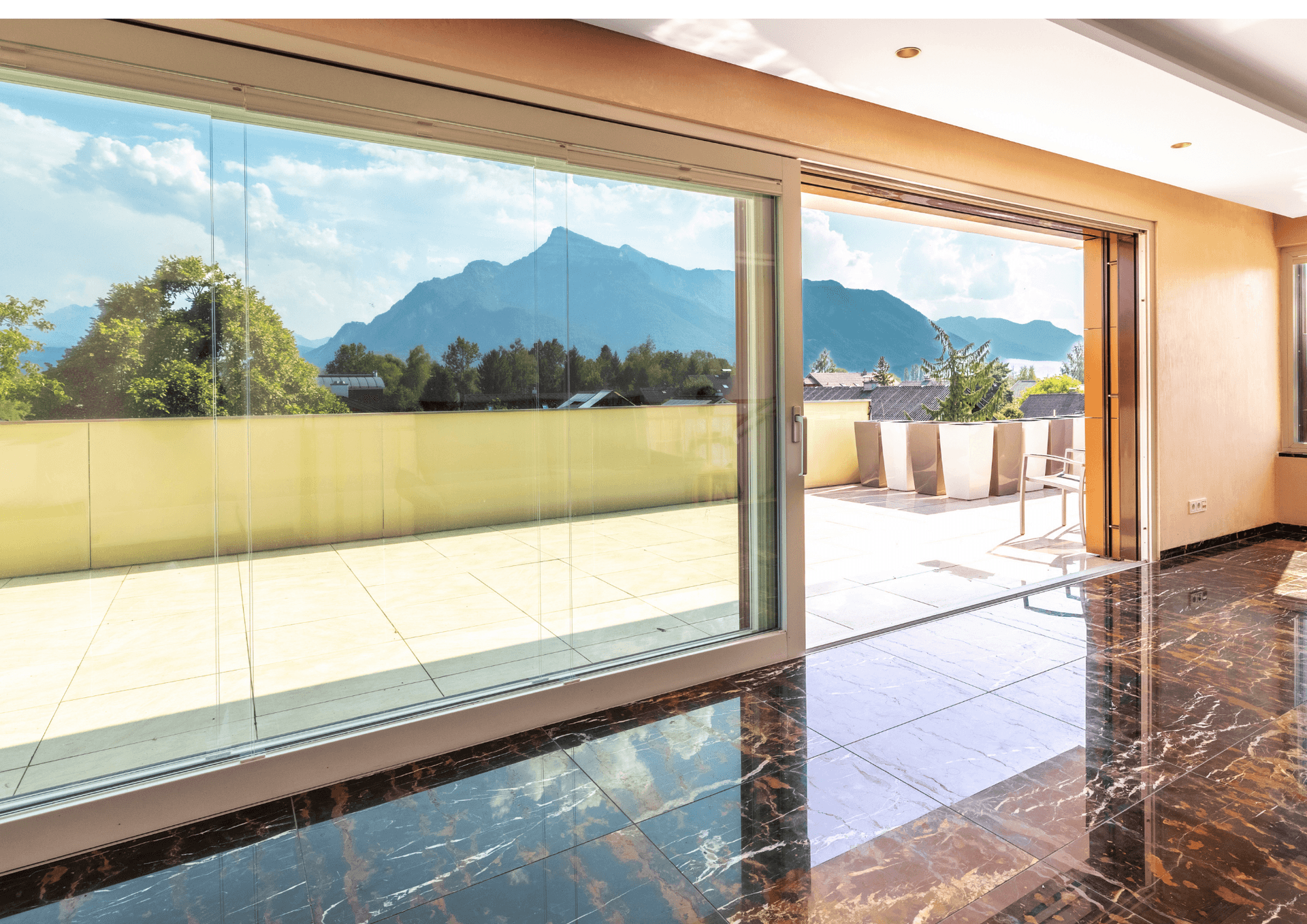 Heller Innenraum mit glänzendem Marmorboden und Zugang zu einer Terrasse mit Bergblick.