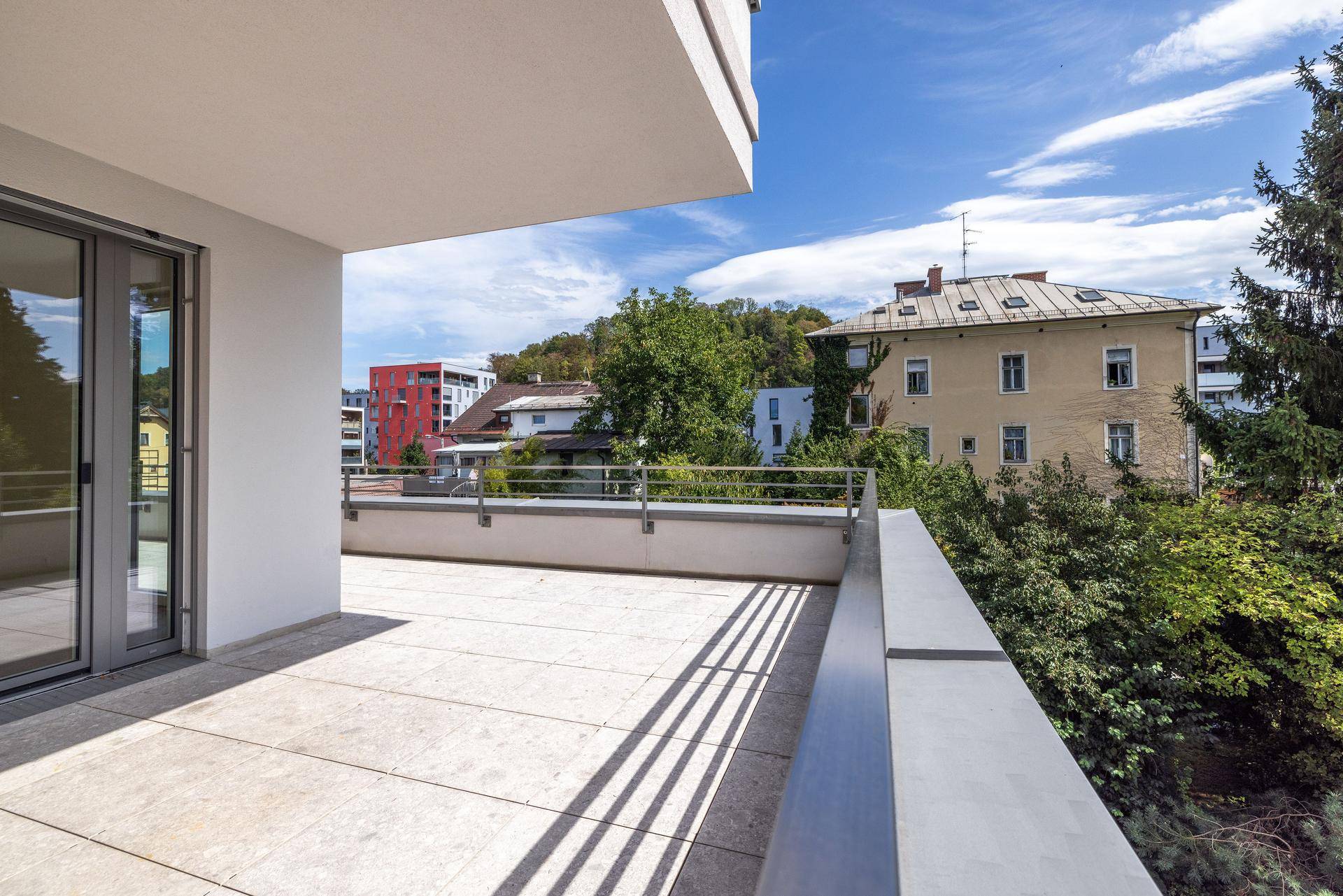 Geräumige Terrasse mit Fliesenboden und weitem Blick auf die umliegende Bebauung und Natur.