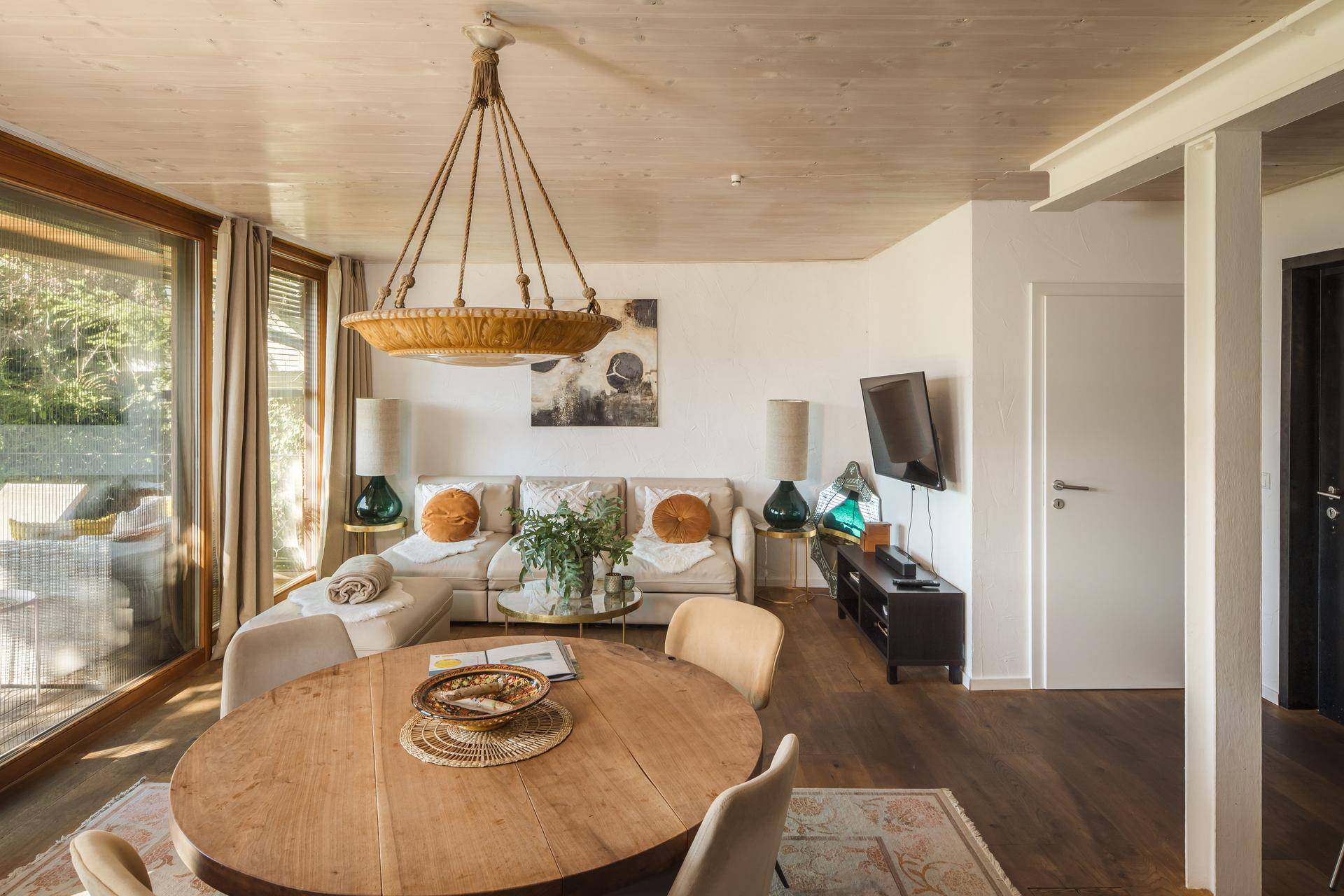 Gemütlicher Wohn- und Essbereich mit bequemer Couch, Holztisch und großen Fenstern mit schöner Aussicht.