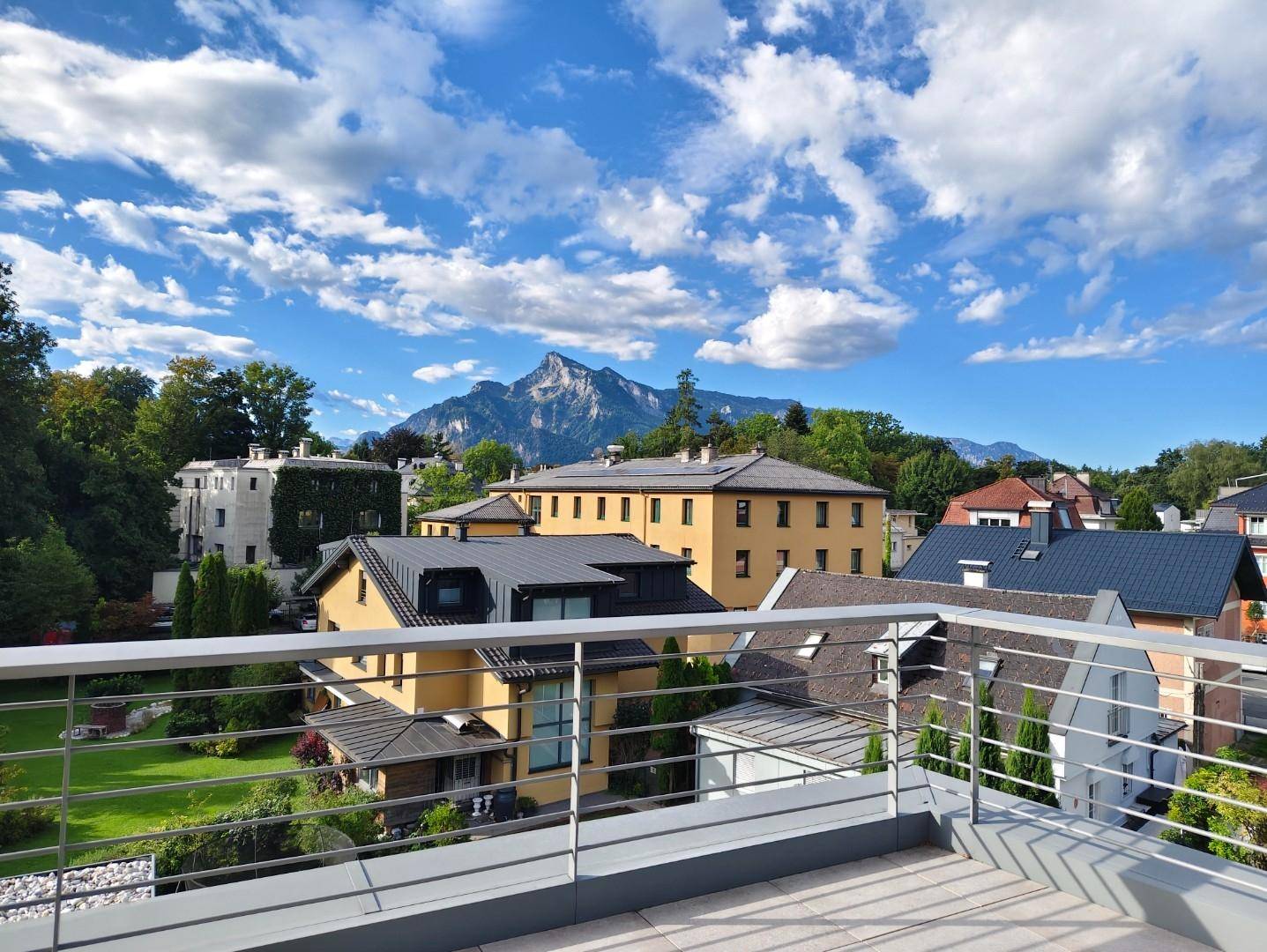 Sonniger Terrassenbereich mit weitem Blick auf die umliegende Berglandschaft und grüne Umgebung.
