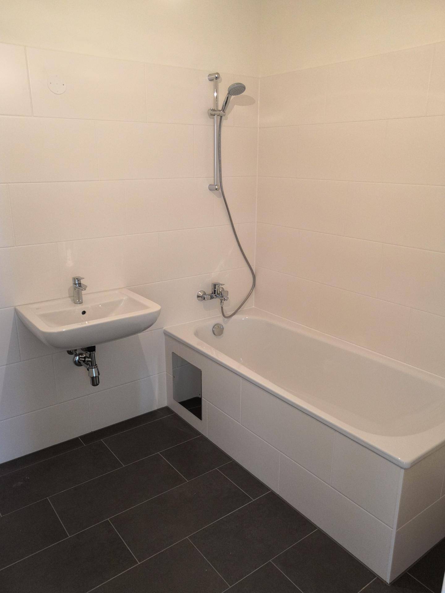 Modernes Badezimmer mit Badewanne, Waschbecken und weißen Wandfliesen.