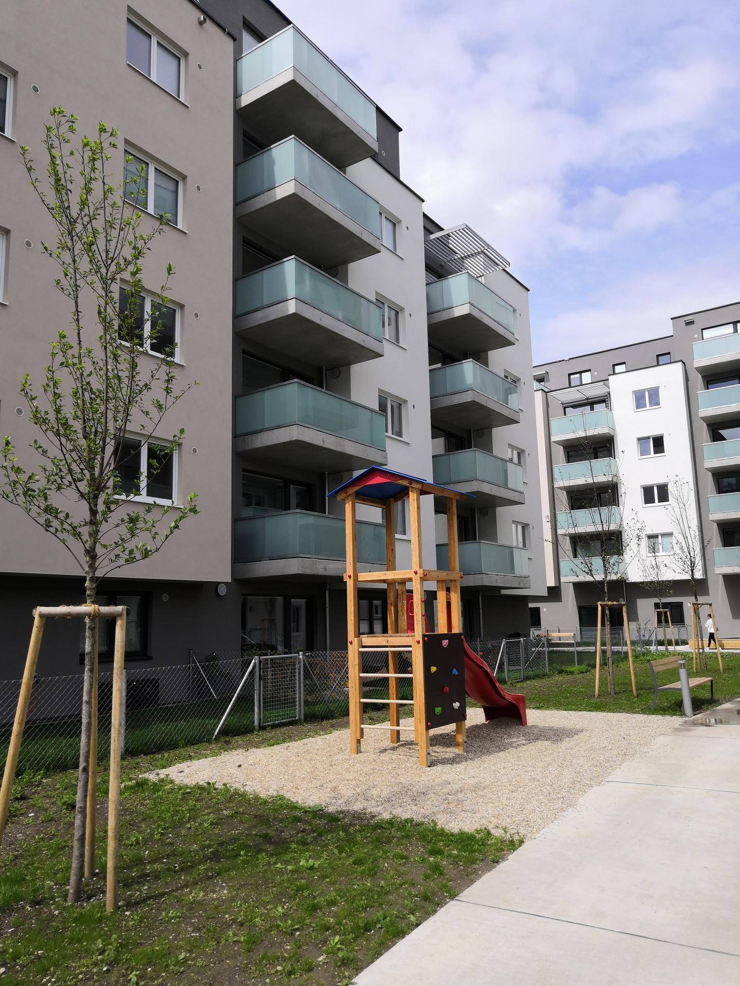 Moderne Wohngebäude mit Balkonen und einem Spielplatz im Vordergrund.