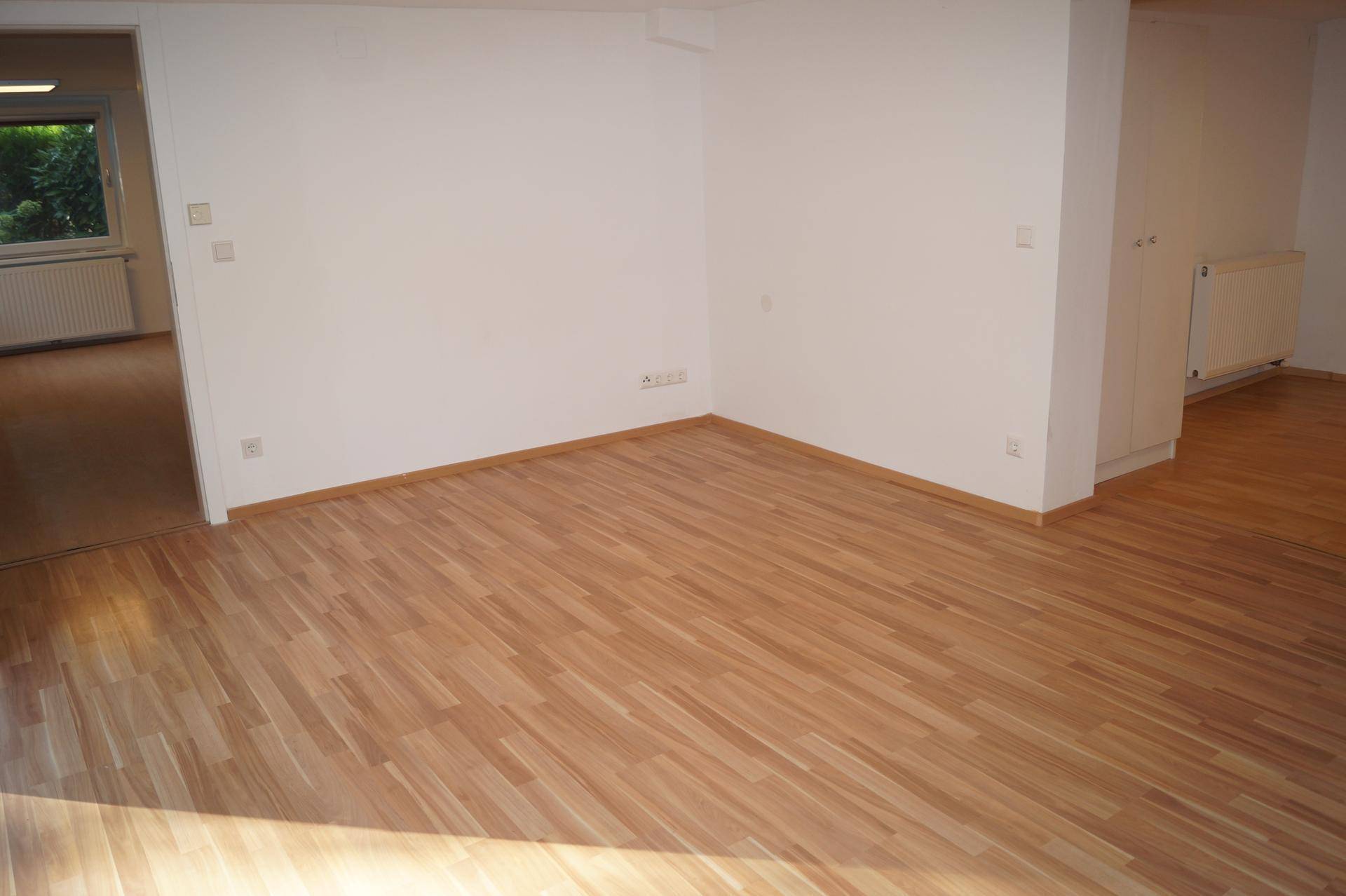 Geräumiger, heller Raum mit Laminatboden und weißen Wänden, bereit zur Einrichtung.