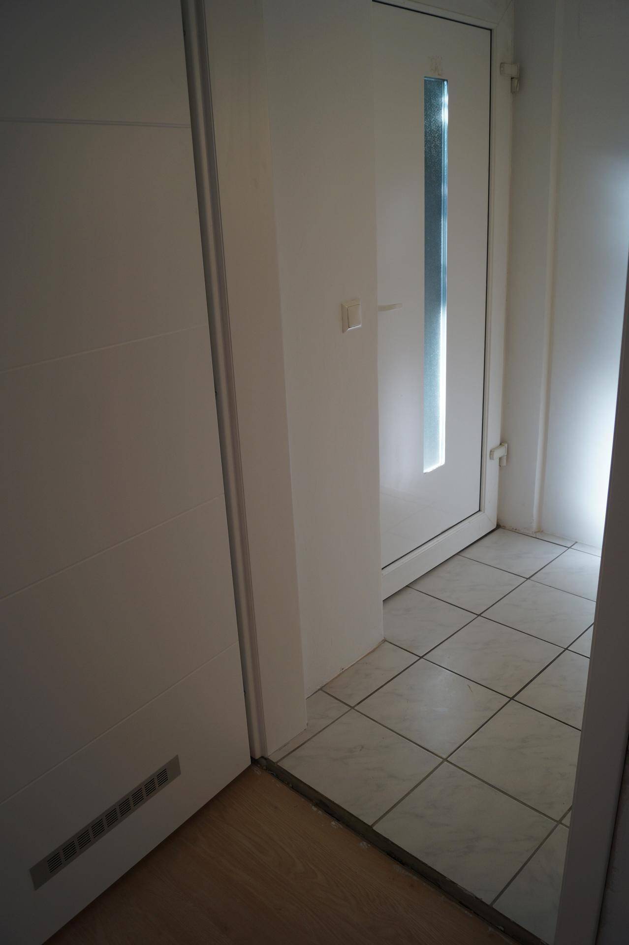 Eingangsbereich mit Fliesenboden, einer Innentür und einer Außentür mit Glaseinsatz.