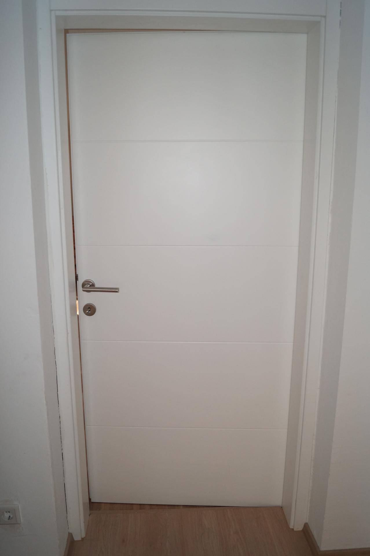 Moderne weiße Innentür mit horizontalen Rillen, passend zu einem zeitgemäßen Design.